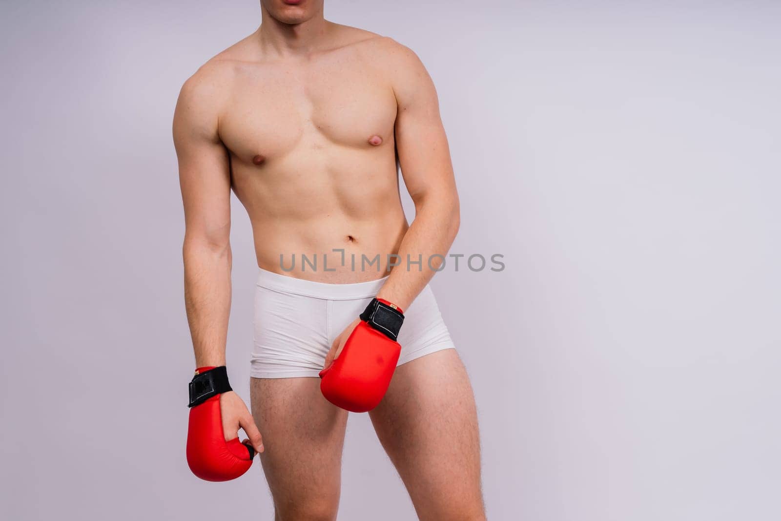 Bodybuilders boxing gloves on a white background and white pants athlete model