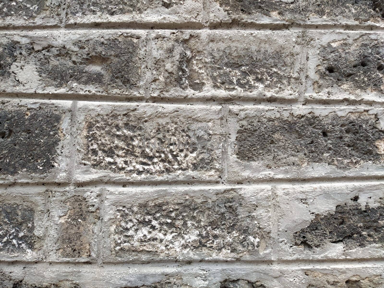 Weathered aged stone masonry of old house. Ancient brick wall background. Old uneven scratched stone bricks texture. Turkish building wall. Rough limestone wall backdrop.