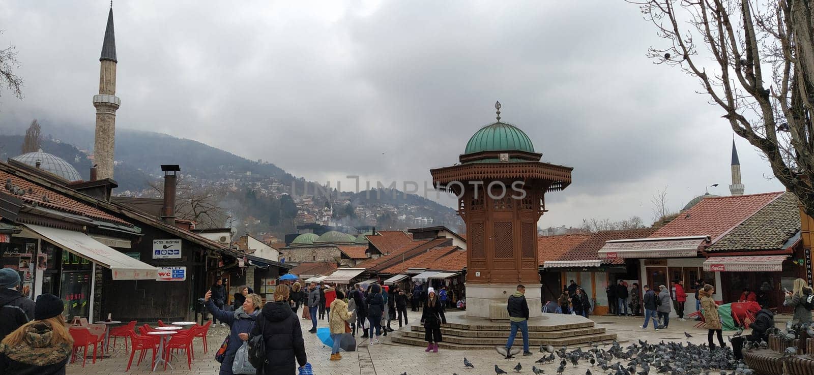 Sarajevo, Bosnia and Herzegovina, March 8, 2020, people walk the central streets of Sarajevo feeding pigeons. Bascarsija and square. Islamic landmarks and tourist sites. Birds walk on the pavement.