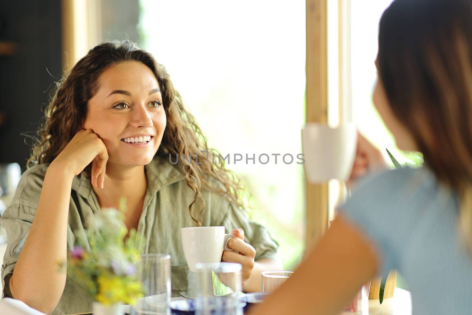 Two friends talking at breakfast drinking coffee in a restaurant