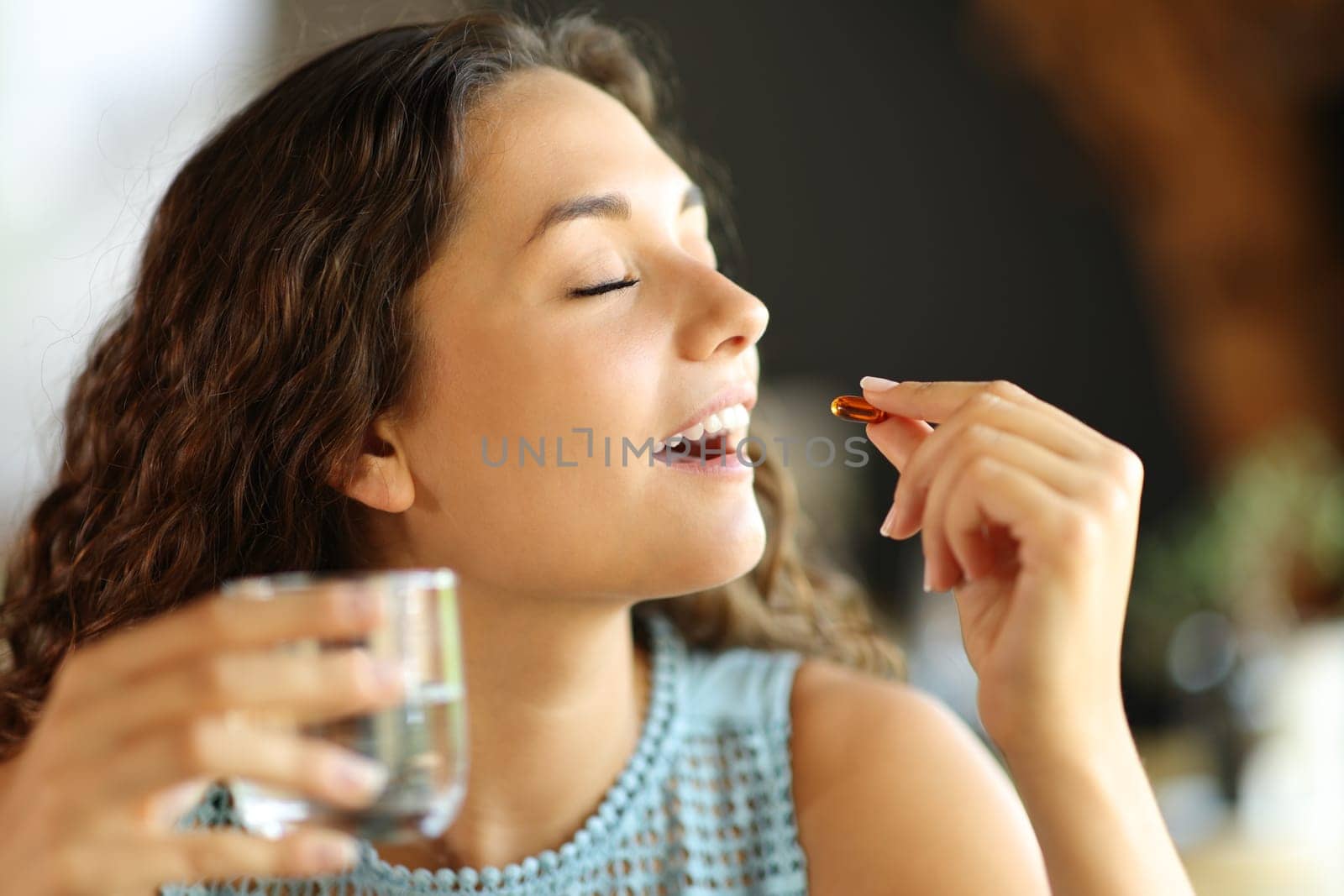 Happy woman eating a vitamin pill in a restaurant