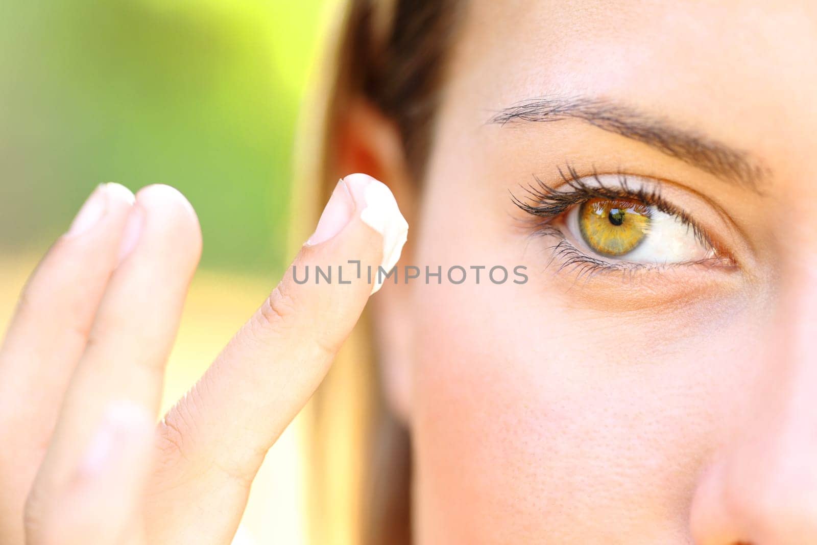 Close up of a woman with beauty eyes applying moisturizer