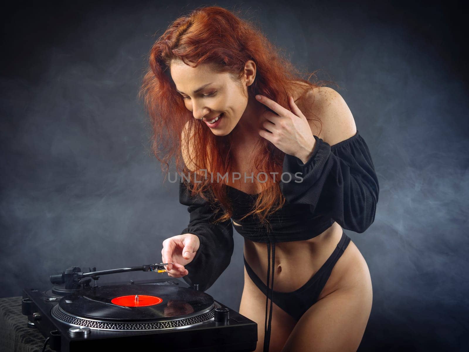Beautiful woman about to put the needle down on the vinyl record spinning on her record player..