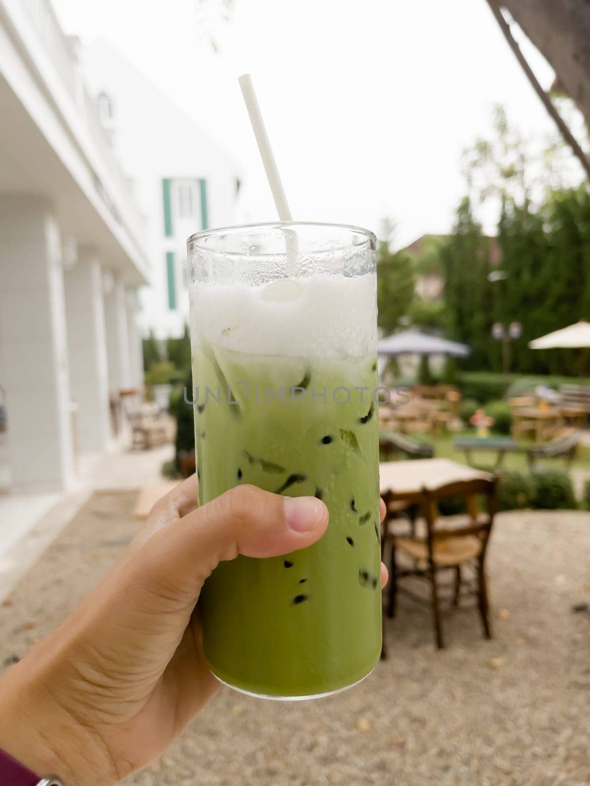 Hand holding glass of iced matcha green tea, stock photo