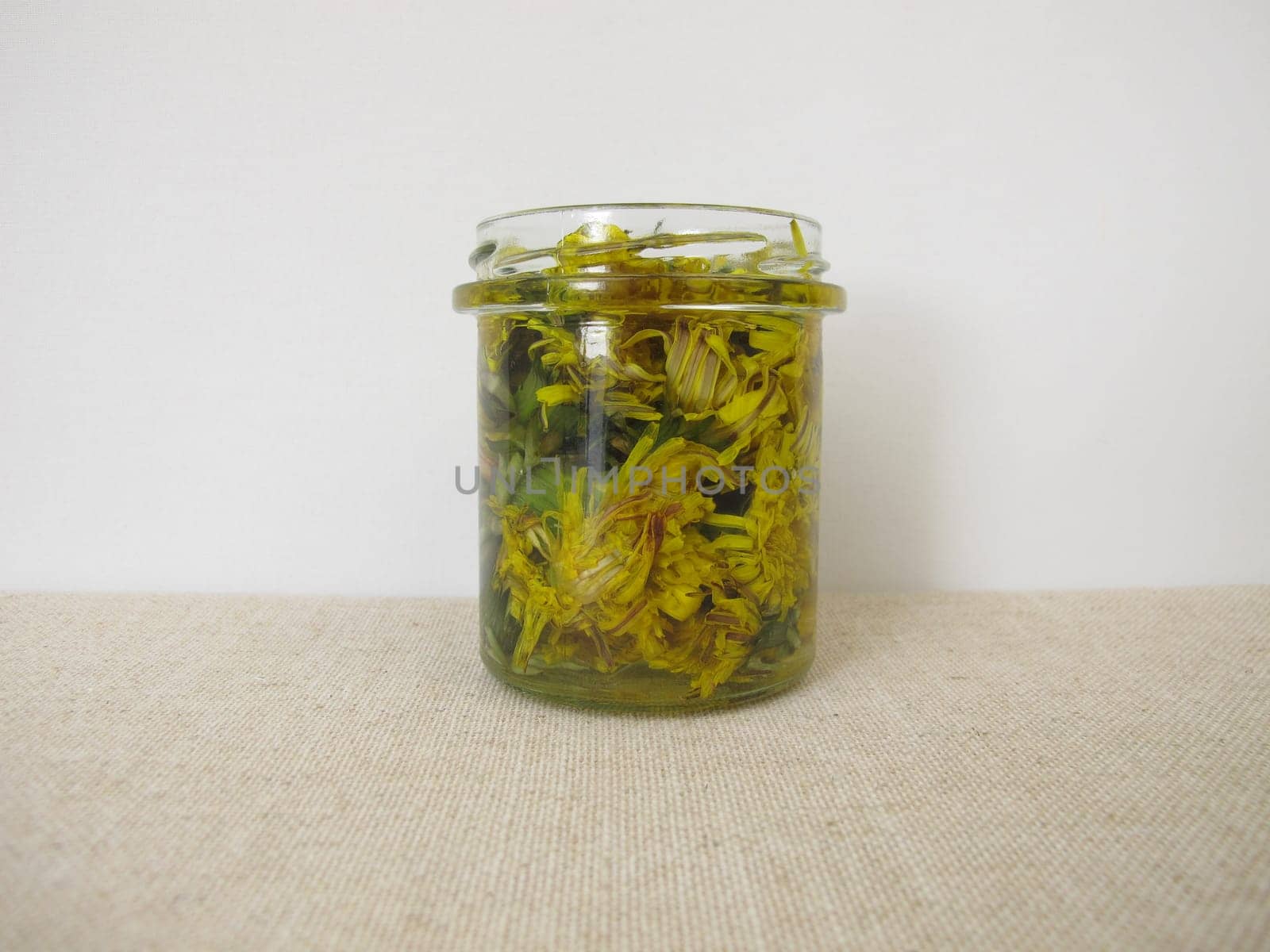 Tincture with dandelion flowers in a glass jar