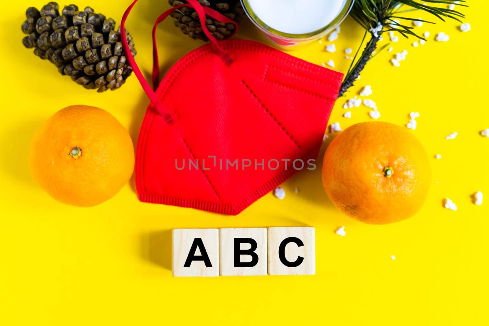 Tangerines lie in medical mask among the branches of the Christmas tree, word Abc wooden cubes