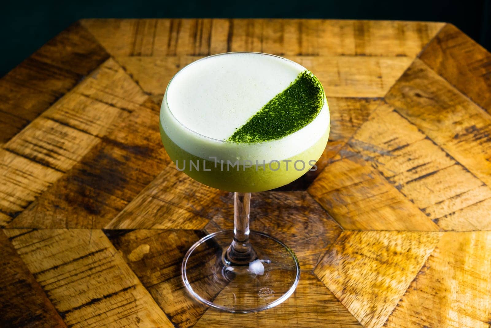 Stemmed cocktail glass with alcoholic drink, closeup isolated on black. Template design