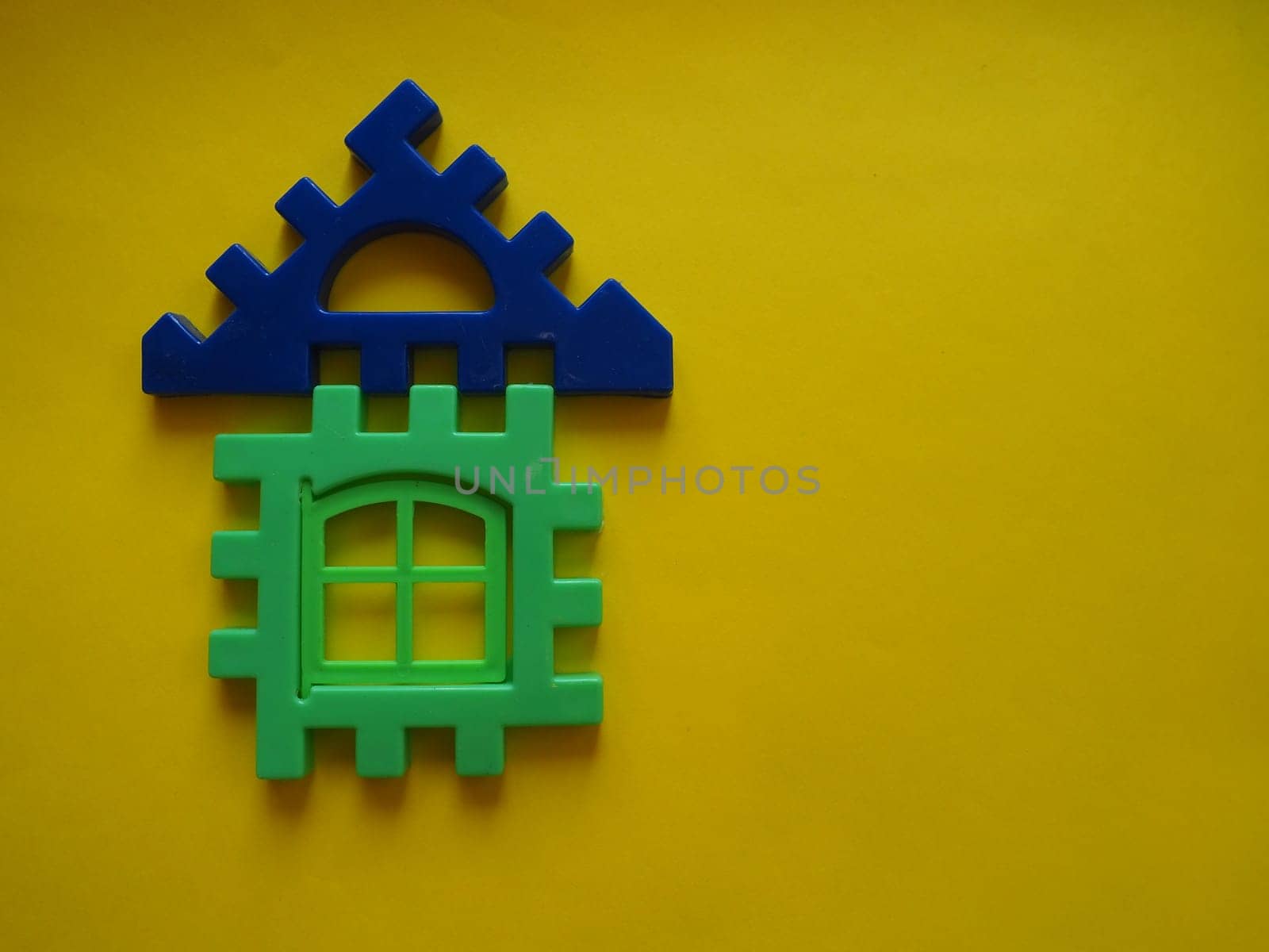 Multicolored plastic kids constructor on yellow background. Colored children's bricks for construction. Flat lay top view copy space. Plastic building blocks background. Developing toys, game