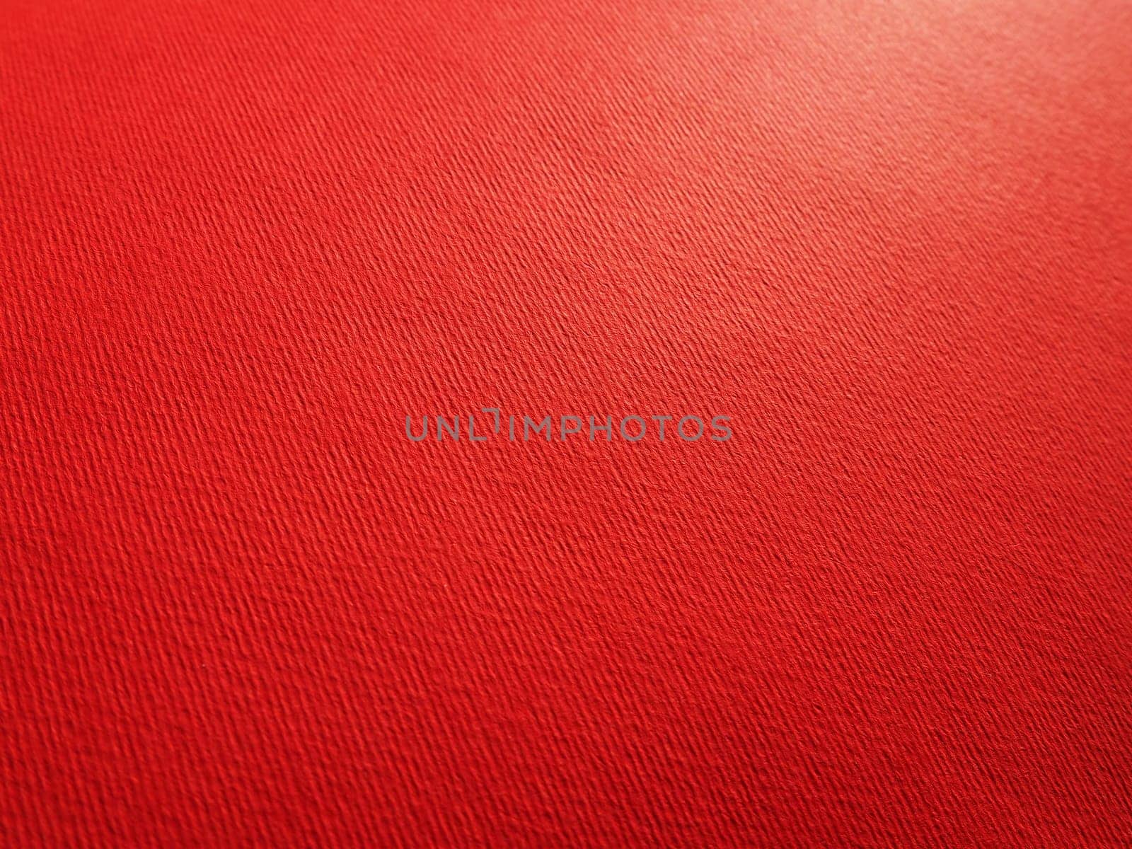Abstract red background with texture. Close-up of paper surface with light and color gradient. Side lighting. Bright crimson backdrop.
