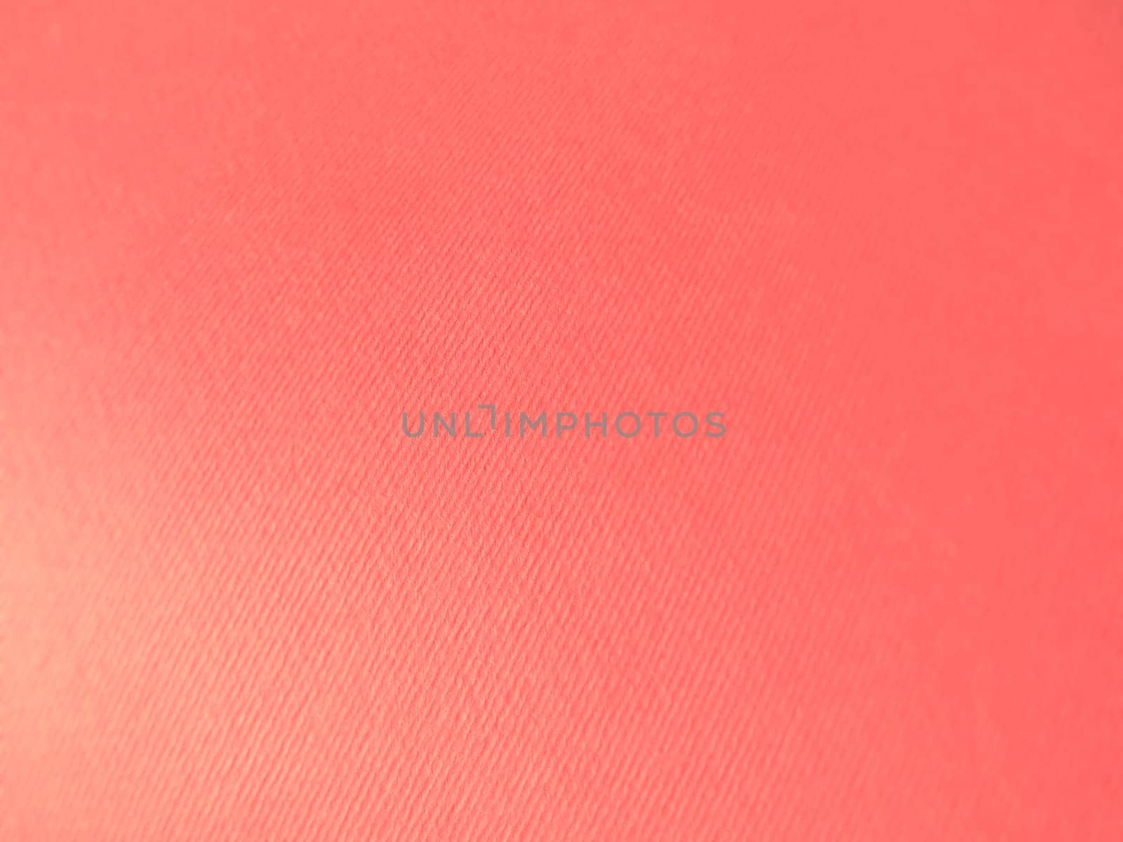Abstract pink background with texture. Close-up of paper surface with light and color gradient. Side lighting. Soft pastel peach or ruddy tone backdrop