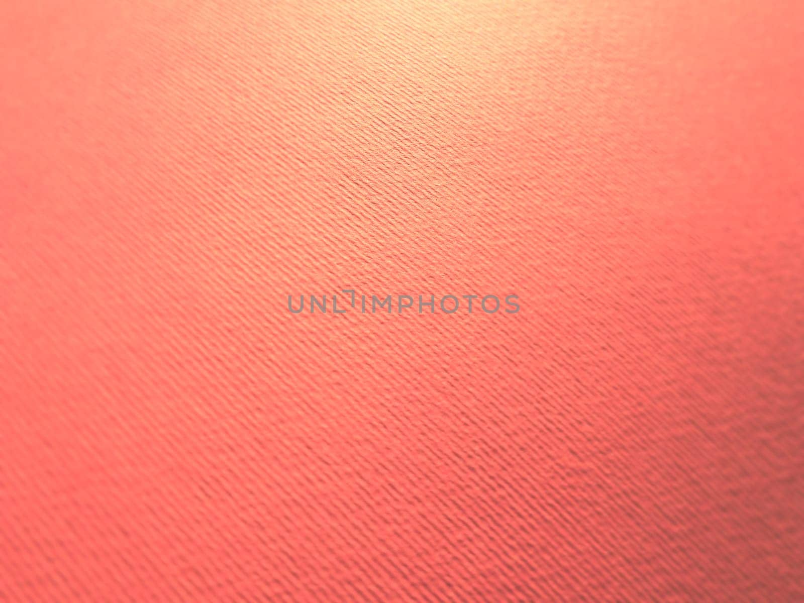 Abstract pink background with texture. Close-up of paper surface with light and color gradient. Side lighting. Soft pastel peach or ruddy tone backdrop