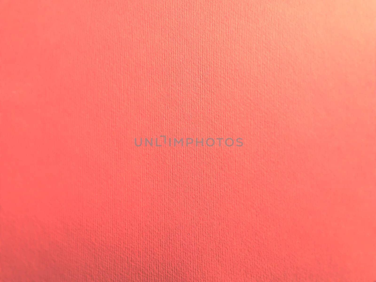Abstract pink background with texture. Close-up of paper surface with light and color gradient. Side lighting. Soft pastel peach or ruddy tone backdrop