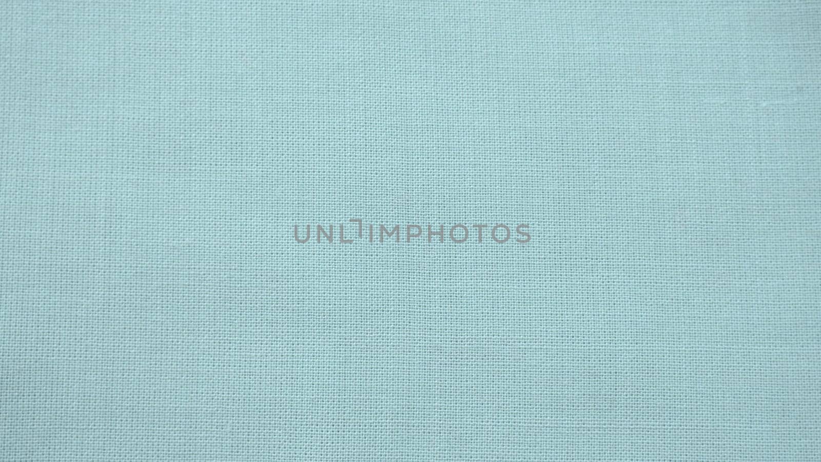 texture of natural light green or blue fabric close-up. The texture of the fabric is made of natural cotton or linen textile material. Green canvas background. Smooth surface of mint-colored fabric.