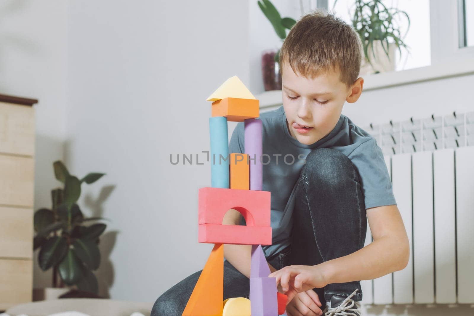 7-10 boy playing at home on the floor with geometric shapes constructor