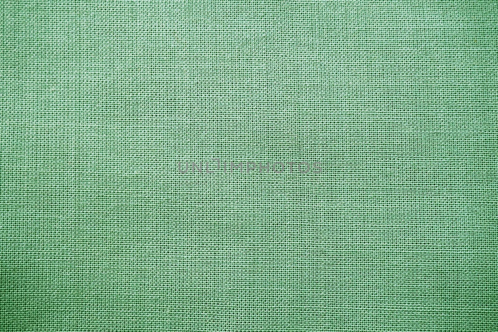 texture of natural green fabric close-up. The texture of the fabric is made of natural cotton or linen textile material. Green canvas background. Smooth surface, smoothed fabric.