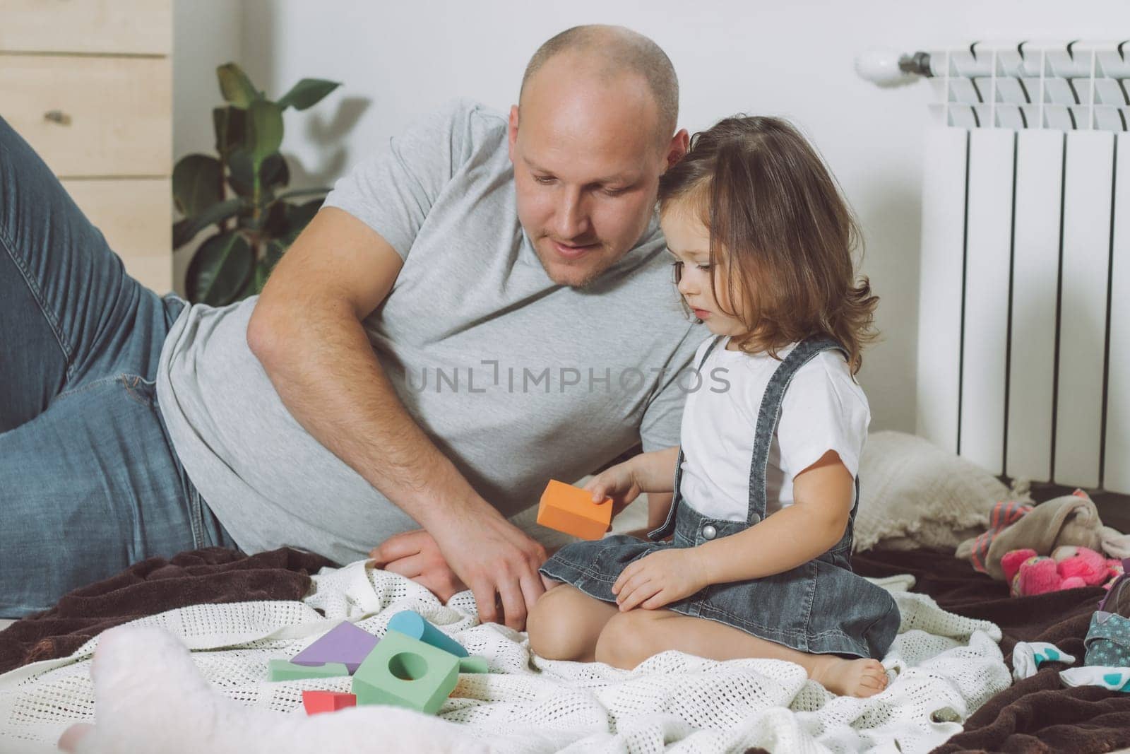 Dad and little girl 2-4 play with constructor sitting on floor at home