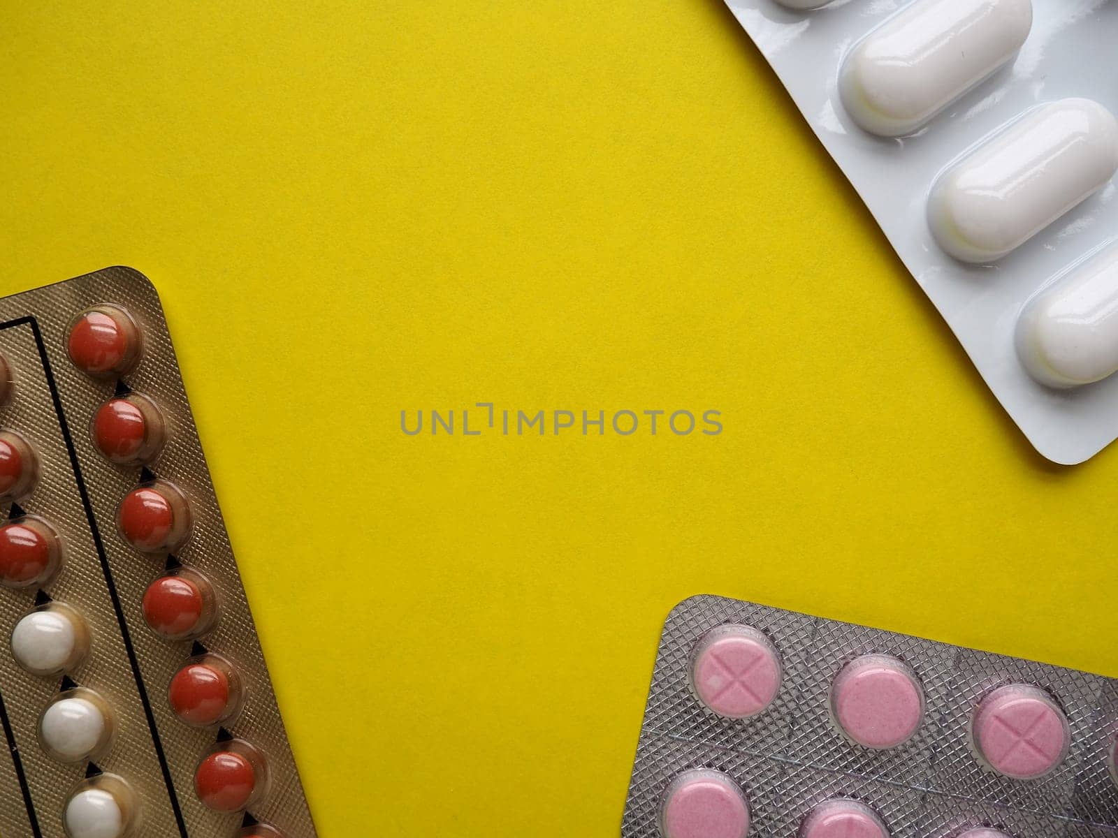 Heap of pills on yellow background. Tablets, vitamins and blisters with capsules for the treatment of diseases. Copy space