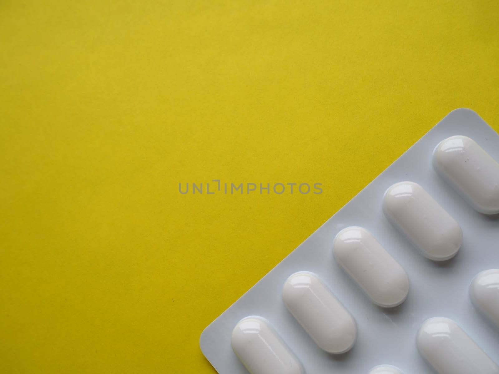 Heap of pills on yellow background. Tablets, vitamins and blisters with capsules for the treatment of diseases. Copy space