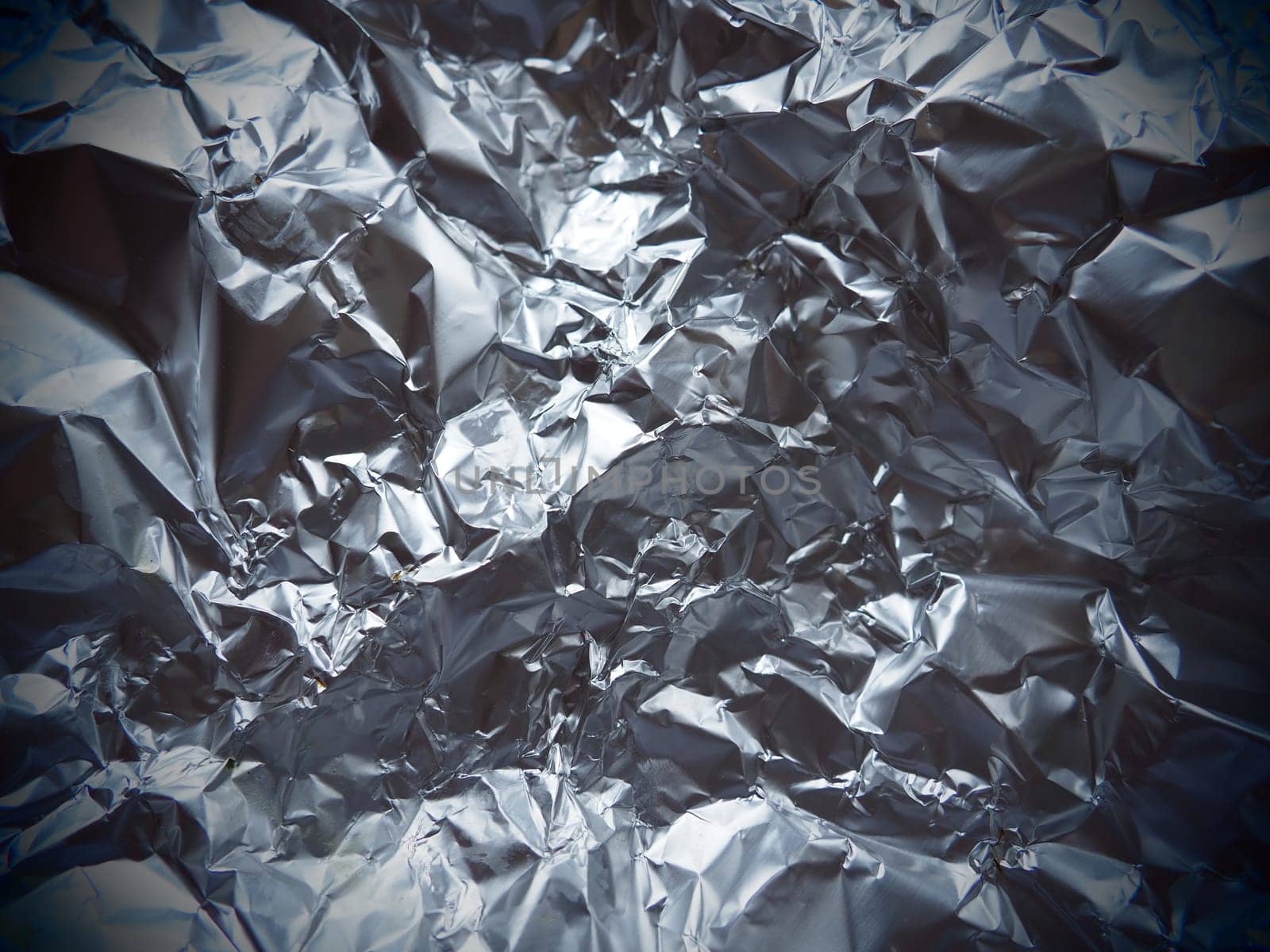 foil close-up. Aluminum silver crumpled foil. Abstract metallic background. Foil for baking food. Background with Vignetting