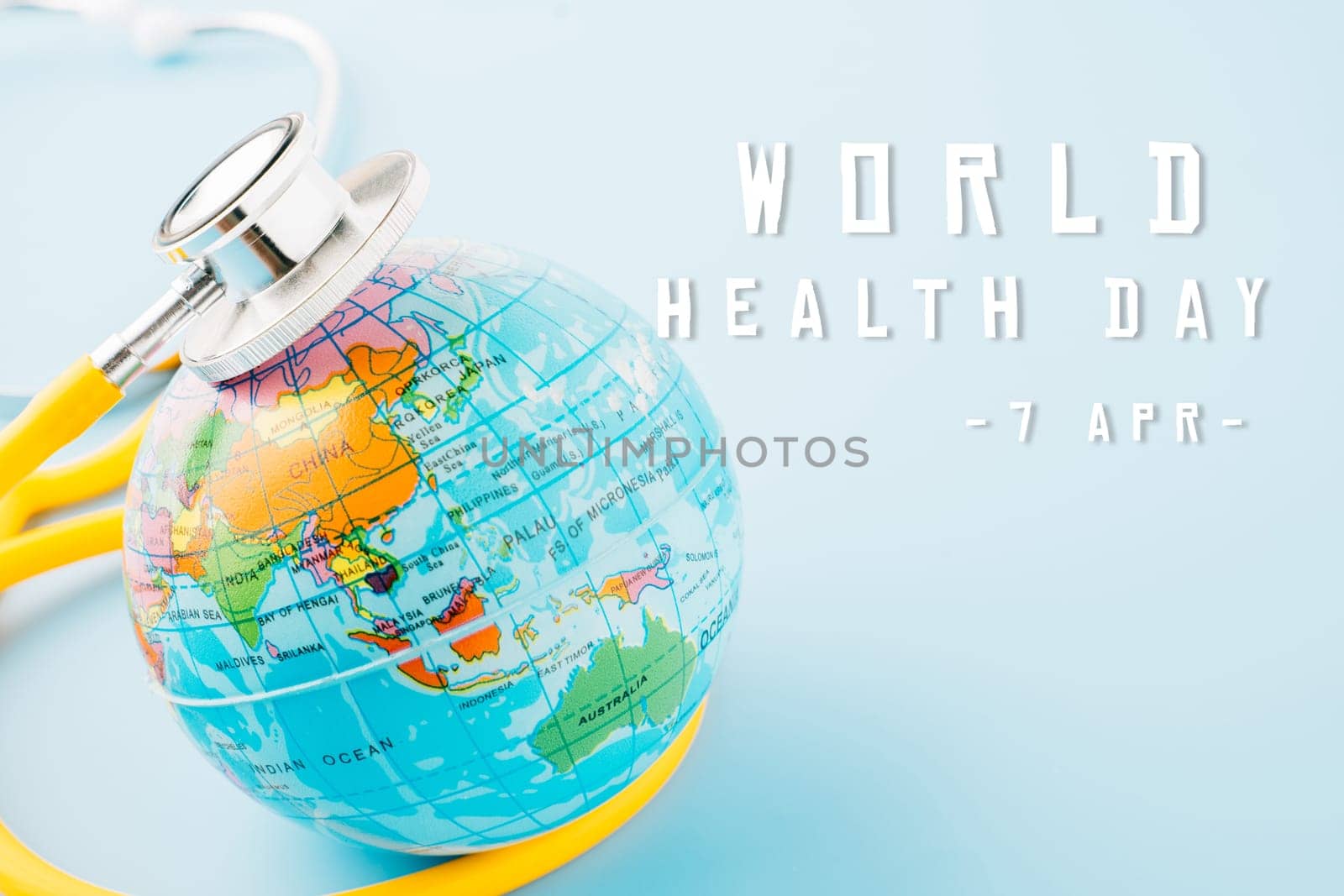 World Health Day. Yellow doctor stethoscope and world globe isolated on pastel blue background with copy space for text, Save world day, Green Earth Environment, Healthcare and medical concept