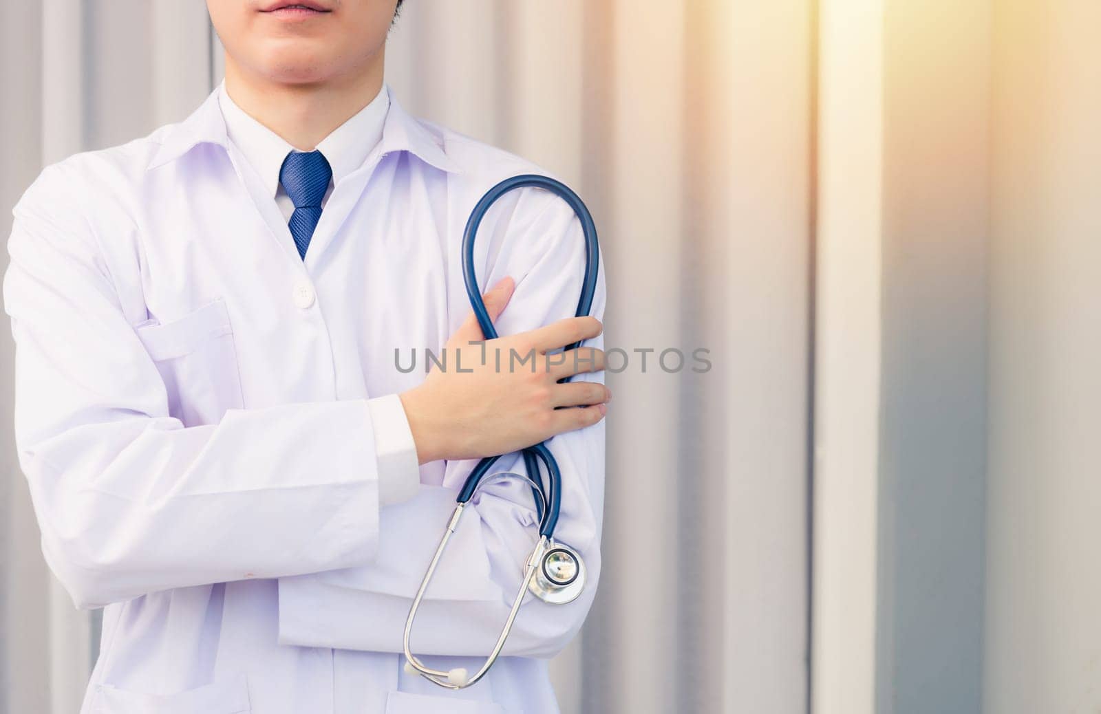 Doctor Day. Nurse man smiling in uniform stand crossed arm hold doctor stethoscope on hand looking to camera with cop space, Healthcare medicine insurance concept