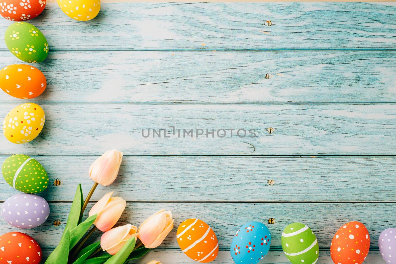 Happy Easter Day Concept. Flat lay holiday banner background web design white colorful easter eggs painted with tulips flowers on blue wood background with empty copy space, overhead, template