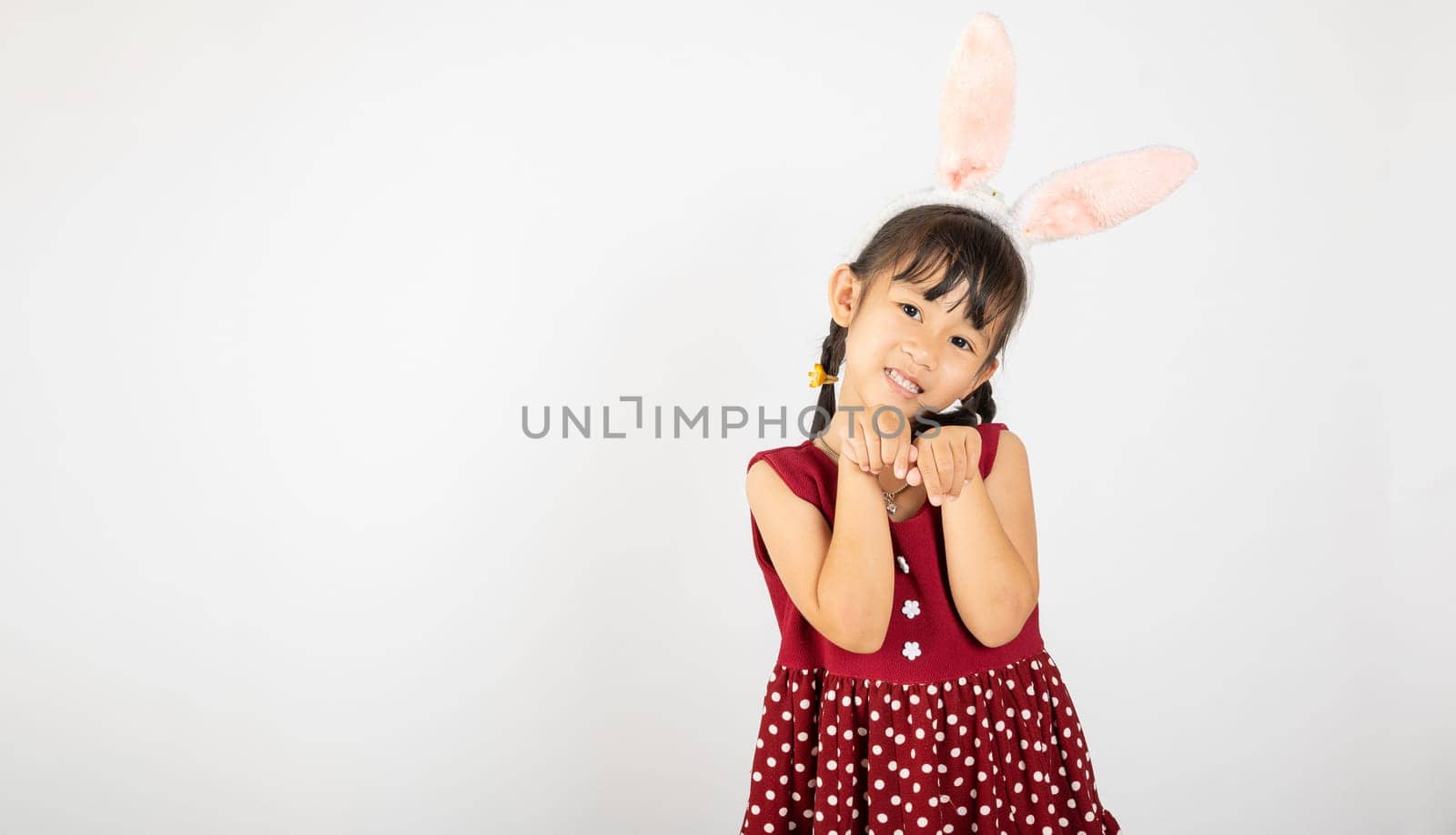 Happy Easter Day. Smile Asian little girl wearing bunny ears make hands act like a rabbit studio shotr isolated on white background with copy space, Easter eeasonal sale and discount
