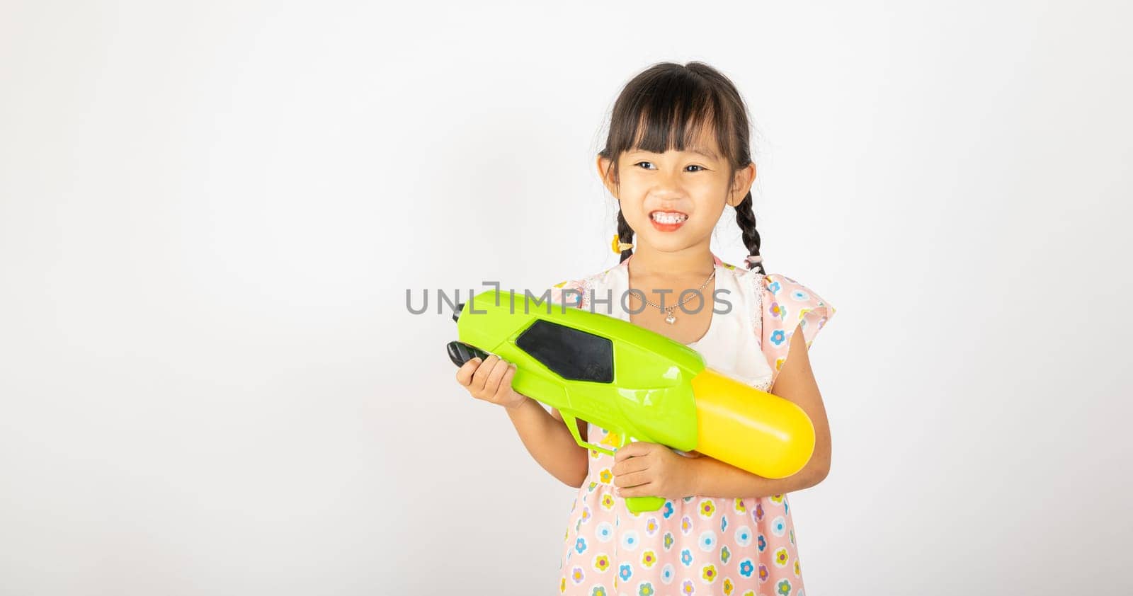 Happy Songkran Day, Asian little girl holding plastic water gun, Thai child funny hold toy water pistol and smile, isolated on white background, Thailand Songkran festival national culture concept