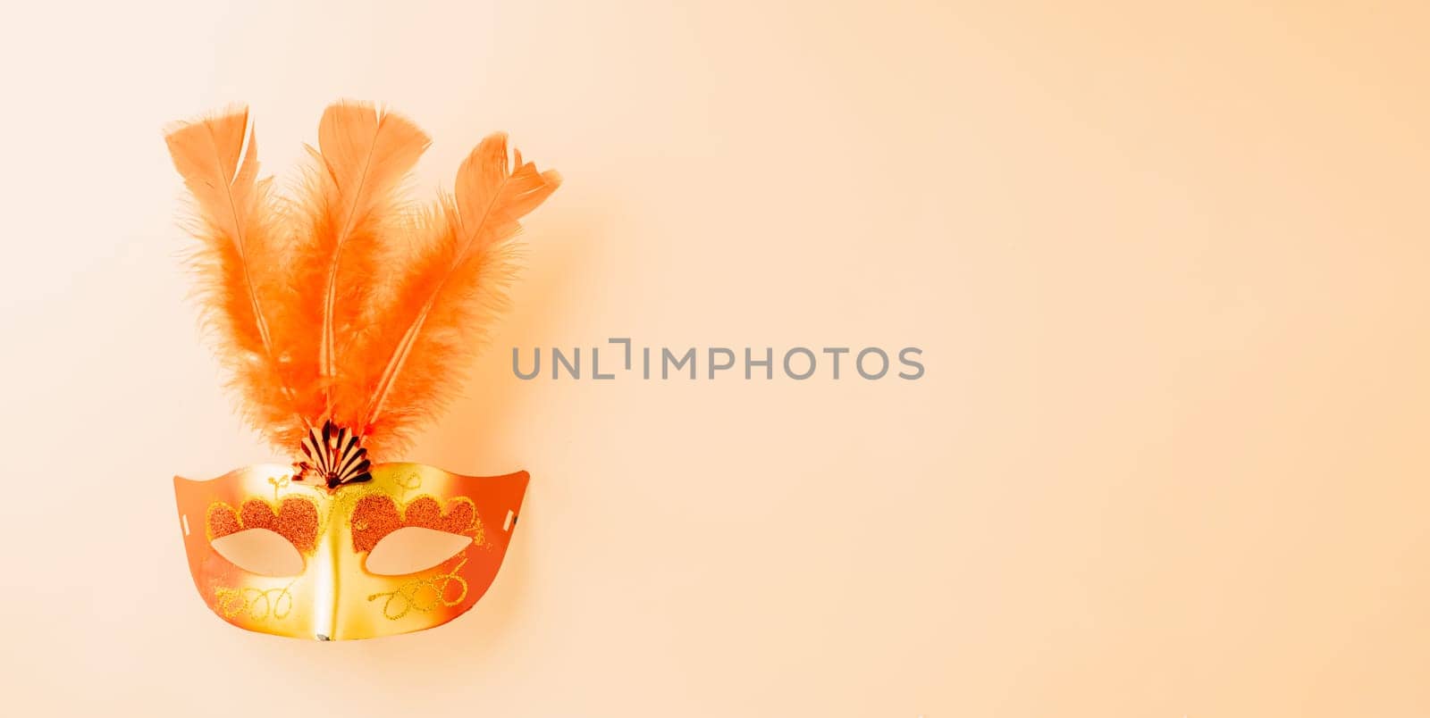 Happy Purim carnival decoration. Top view venetian ball mask with red feather on pastel background with copy space, Masquerade party, Jewish Purim in Hebrew, holiday background banner design