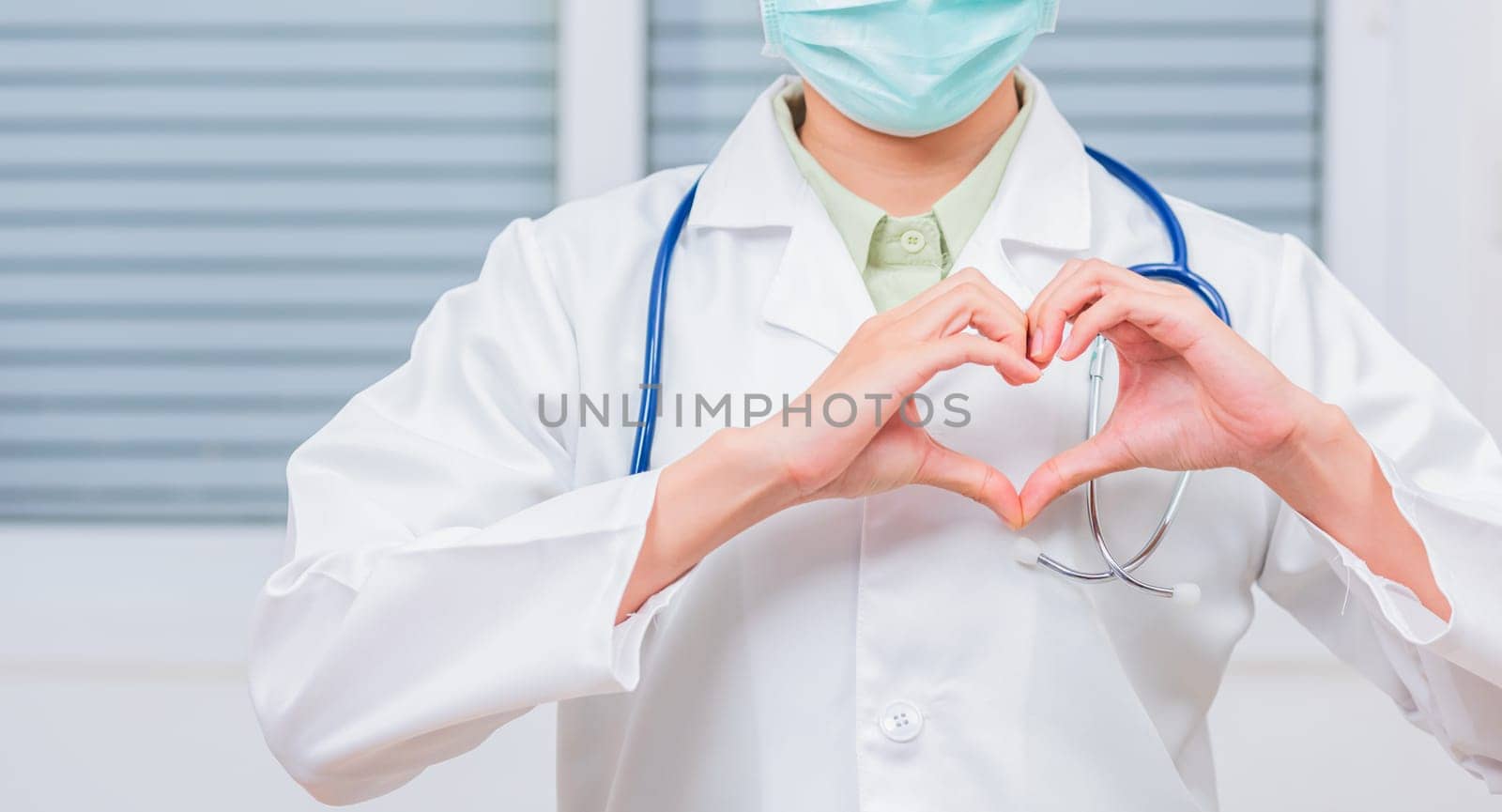Doctor Day Concept. Doctor woman wearing uniform and stethoscope she making heart finger shape, Doctor's hand sign, Healthy medical heart, treatment of heart diseases by palms