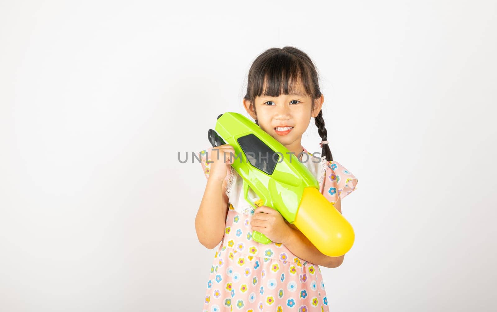 Happy Songkran Day, Asian little girl holding plastic water gun, Thai child funny hold toy water pistol and smile, isolated on white background, Thailand Songkran festival national culture concept