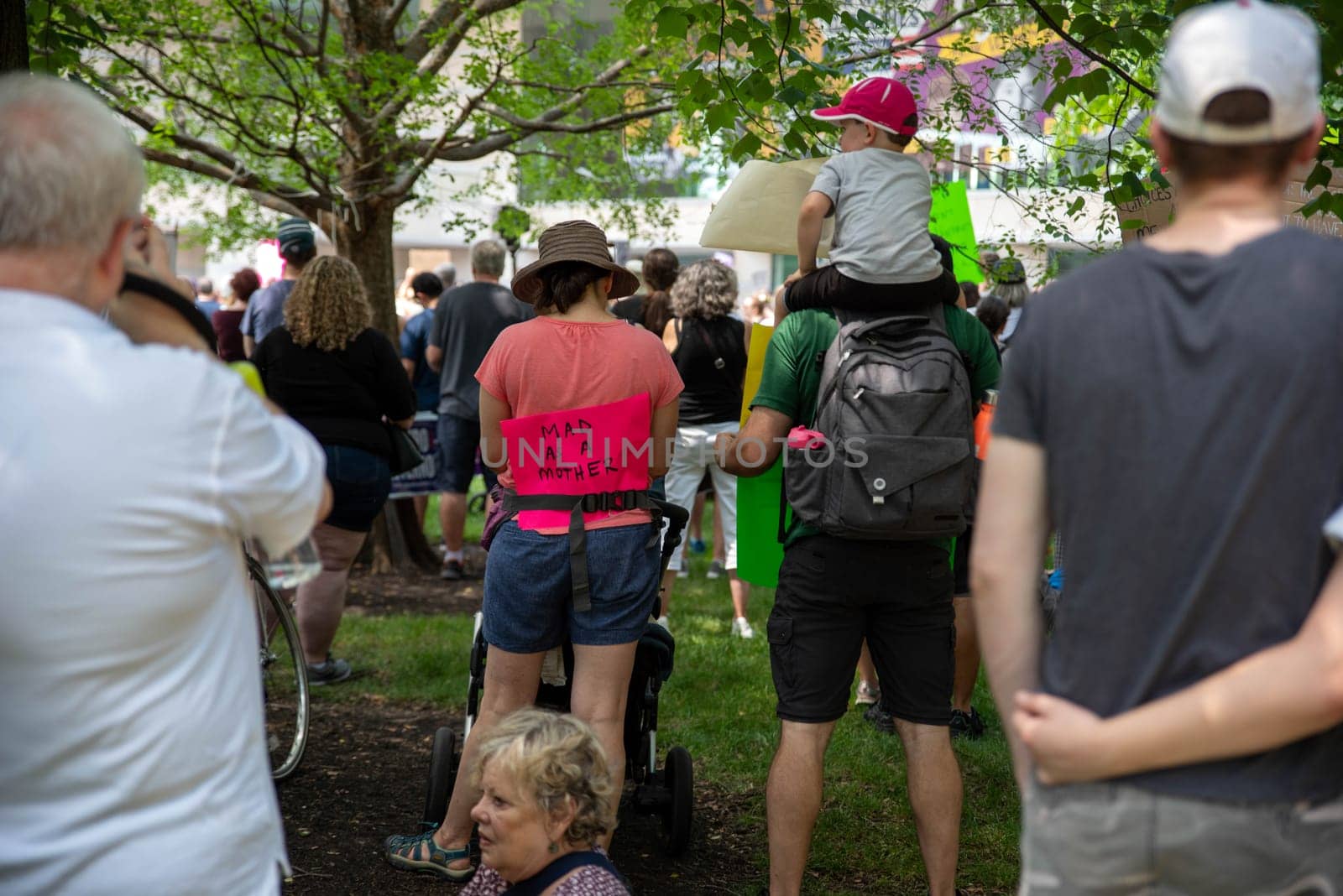 Philadelphia, PA USA - 06-25-2022 National Constitution Center, mom with stroller wears a MAD AS A MOTHER sign next to male partner carrying small child in a crowd at a political pro-choice reproductive freedom rally for Josh Shapiro.