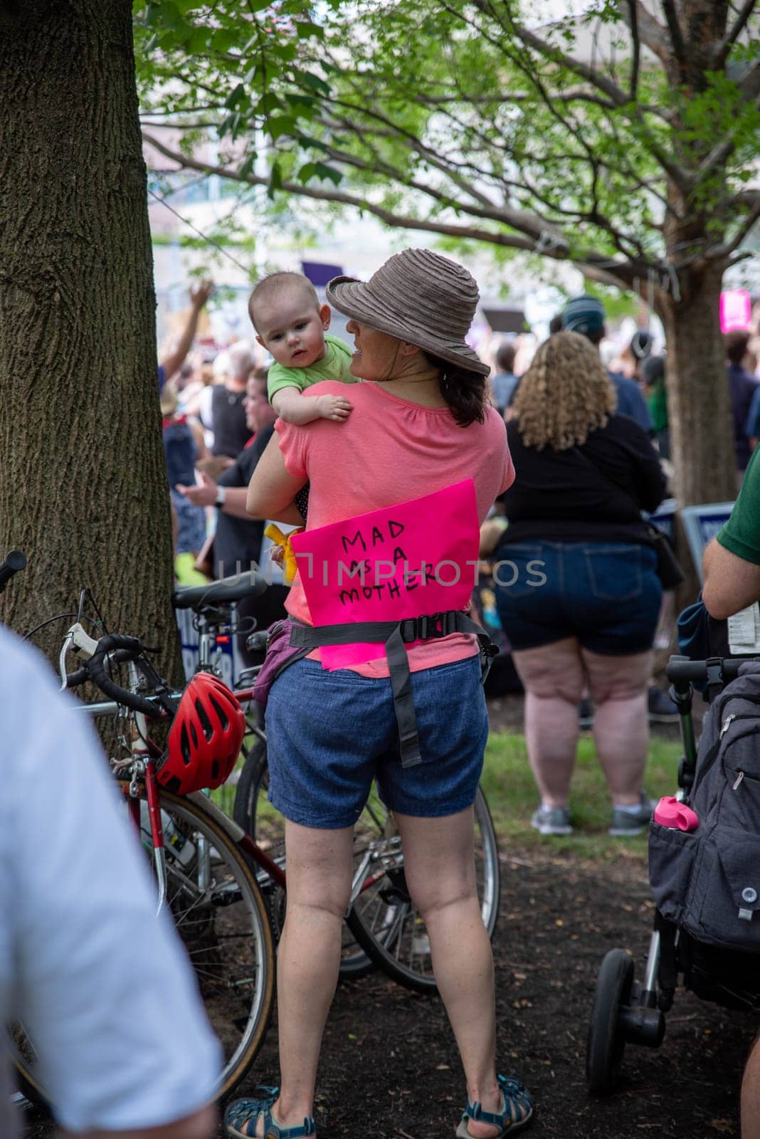 Philadelphia, PA / USA-06/25/2022: MAD AS A MOTHER woman with baby wears a feminist pro-choice sign at pro-abortion rally. Large crowd, cute baby, fabulous feminist image. Editorial use only.