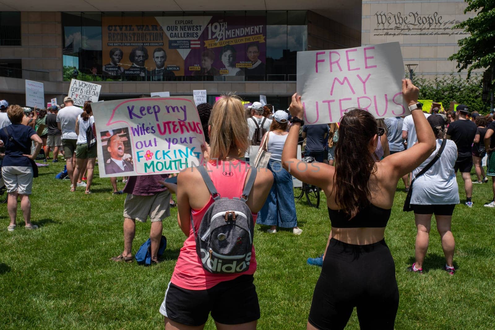 Philadelphia, PA / USA-06/25/2022: Two women in a crowd hold feminist signs at a pro-choice rally FREE MY UTERUS and KEEP MY WIFE'S UTERUS OUT OF YOUR F*ING MOUTH. Josh Shapiro rally. Editorial only