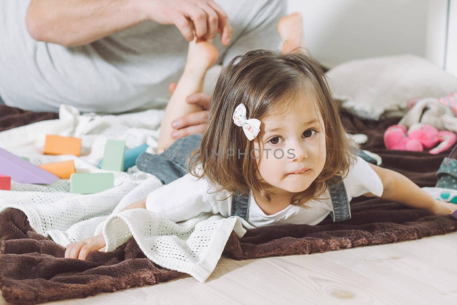 Father plays with little daughter 2-4 on floor. Dad tickles kids feet. Family, having fun