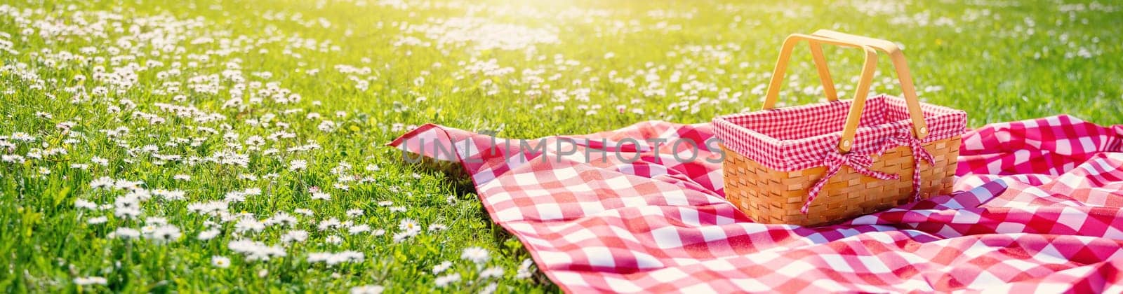 Picnic duvet with empty basket on the meadow in nature. Panoramic view. Concept of leisure and family weekend.