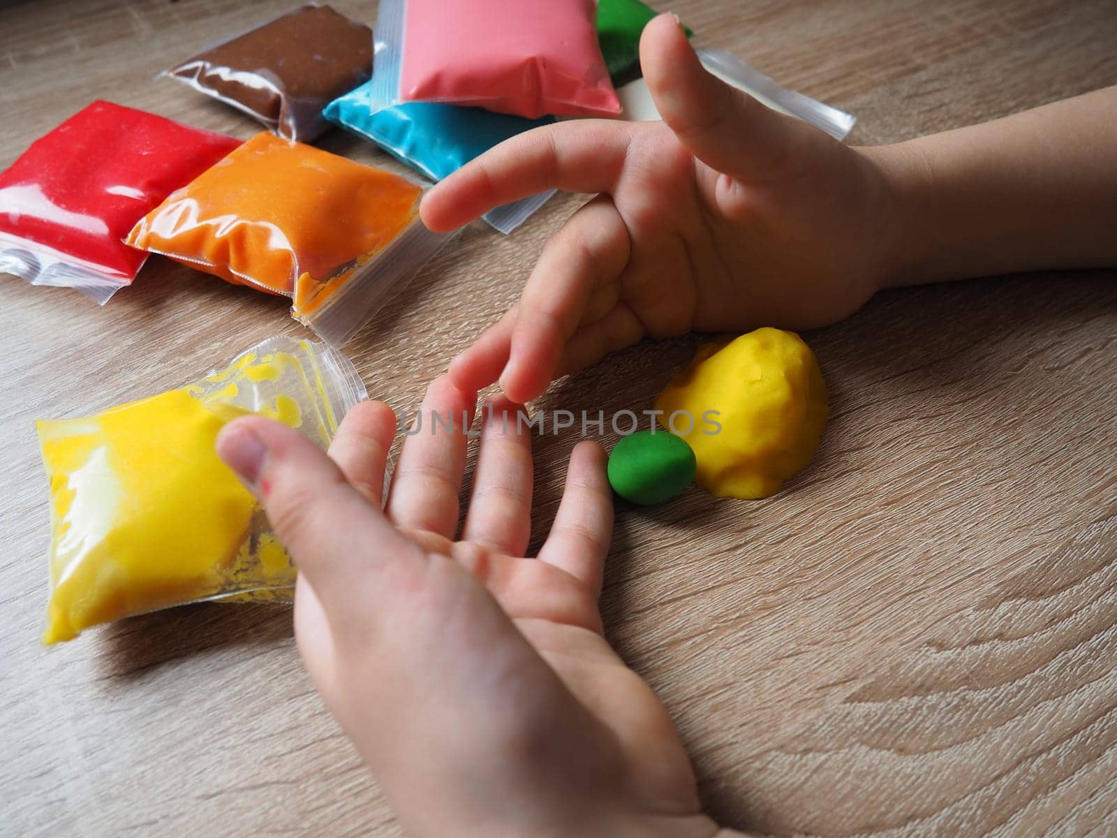 Classes with plasticine. Children's hands crumple soft plasticine. Packages with plasticine are on the table. Creativity for the development of fine motor skills of hands. Creating from plasticine.