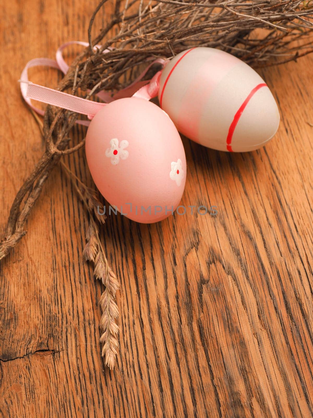 Pink Easter eggs with decoration on a rustic wooden table background with space for text