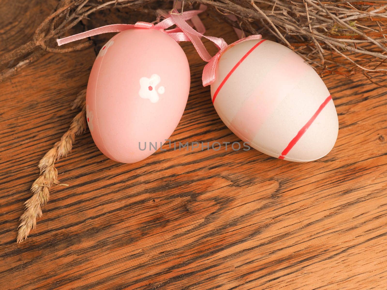 Pink Easter eggs with decoration on a rustic wooden table background with space for text