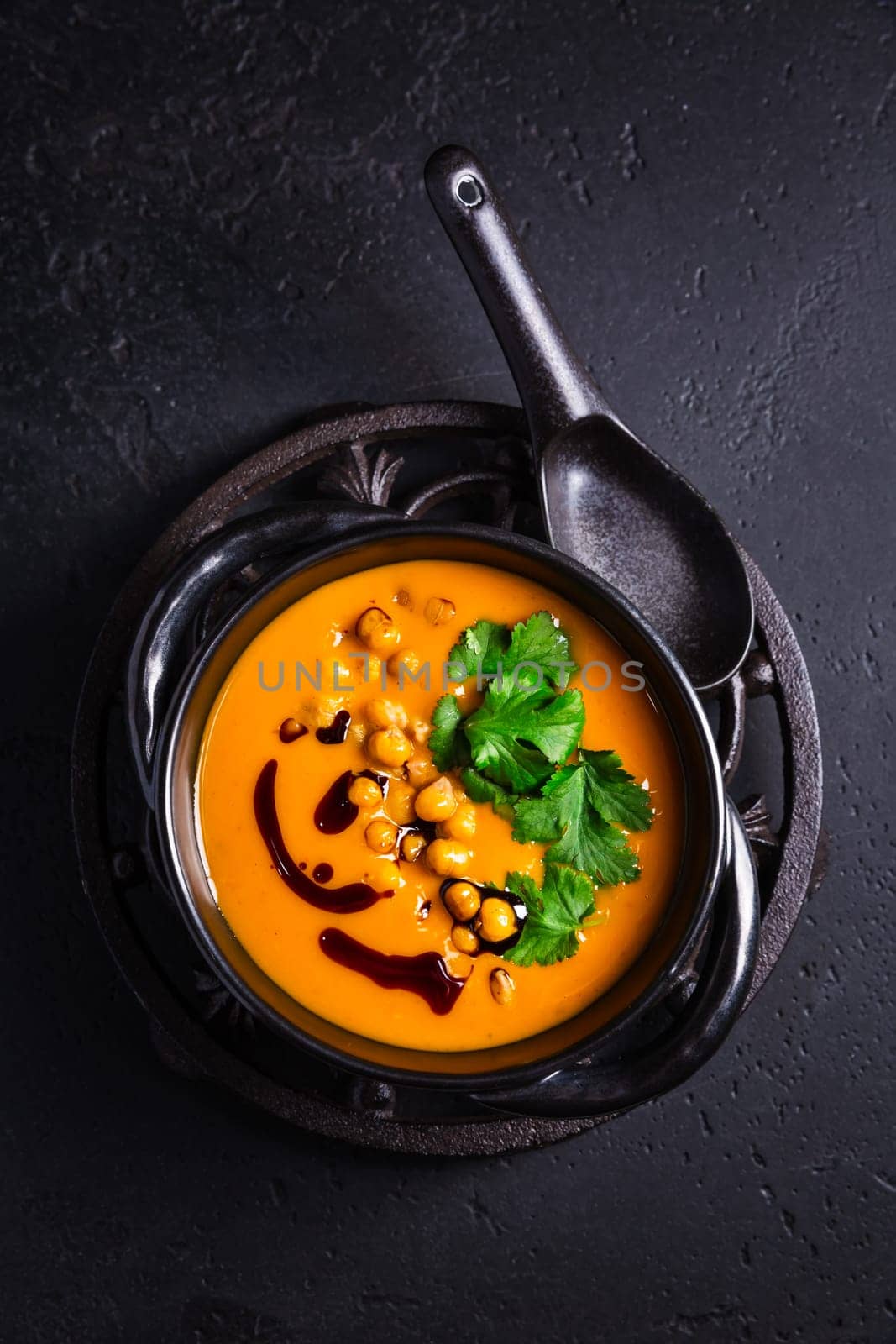 Creamy Pumpkin cream soup with pumpkin seed oil, baked chickpeas and cilantro