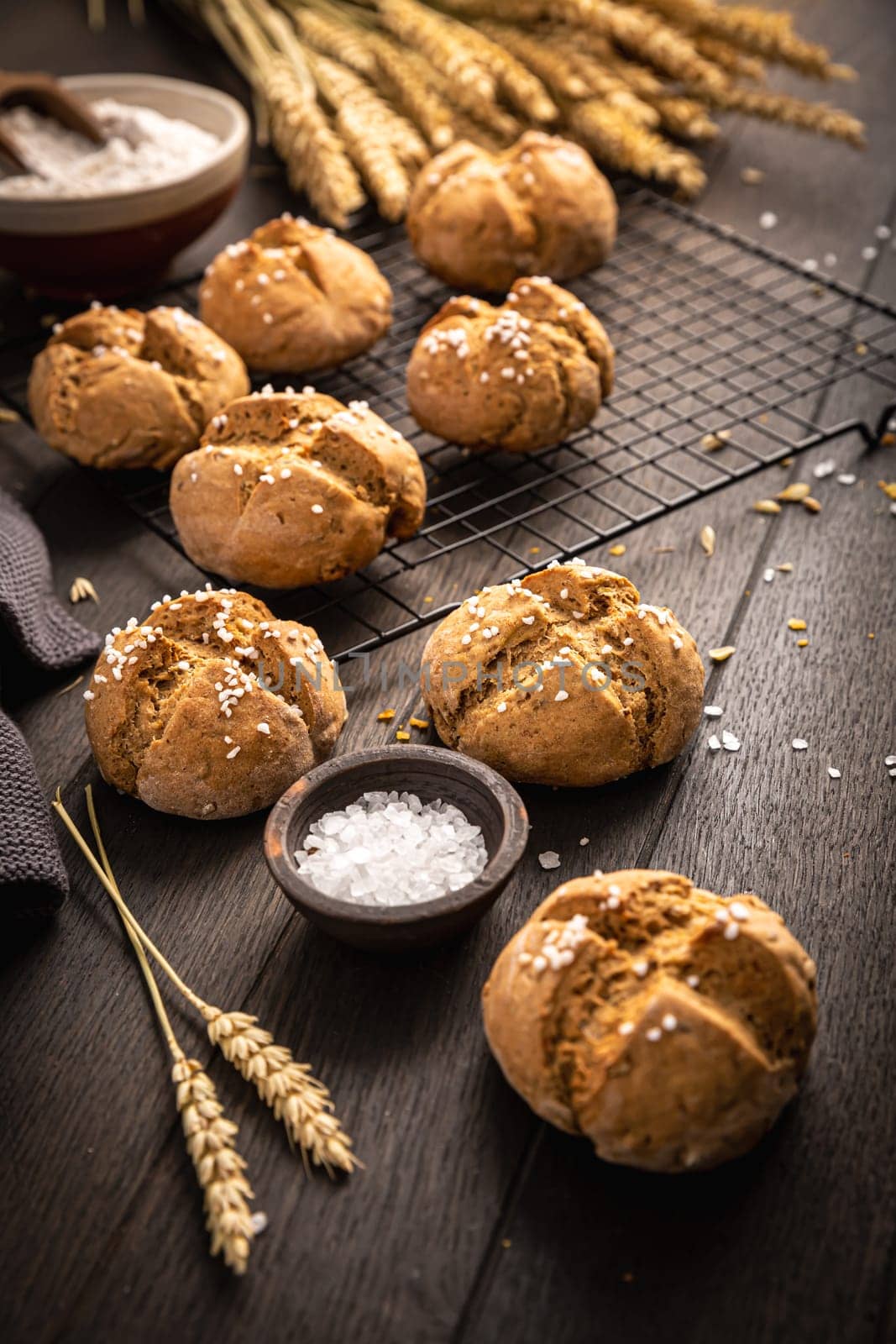 Homemade spelt bread rolls with salt on wooden background