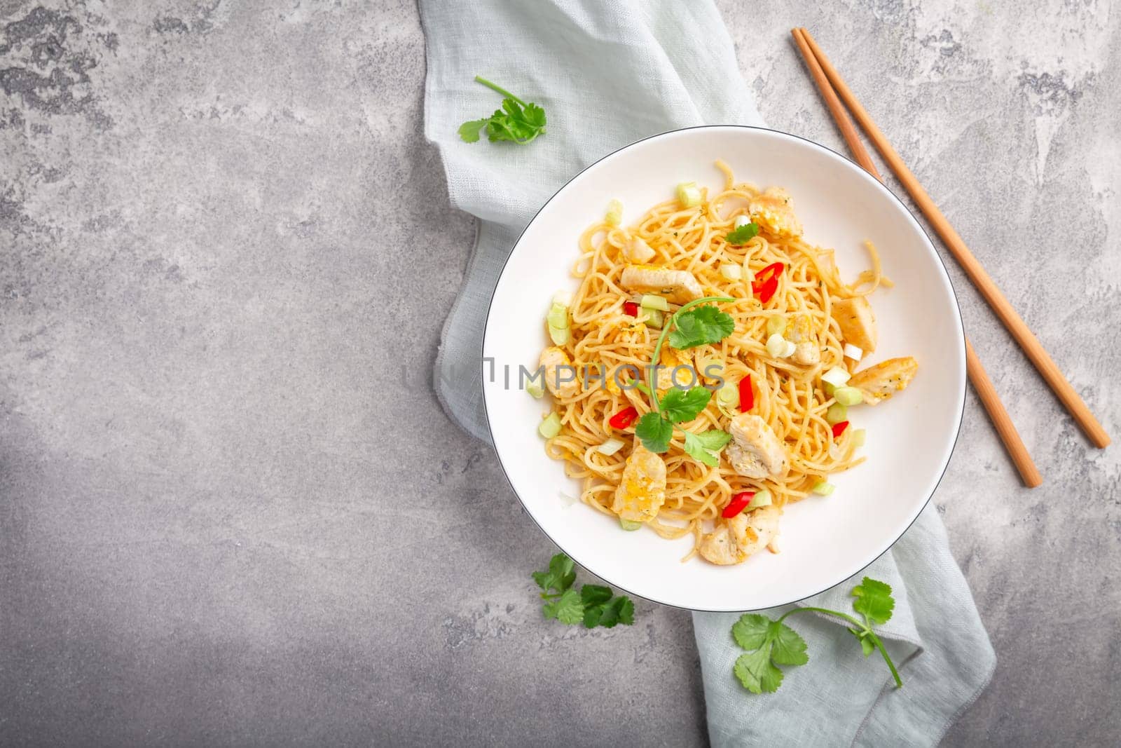 Stir fried noodles with chicken and vegetable in white bowl. Asian style food.
