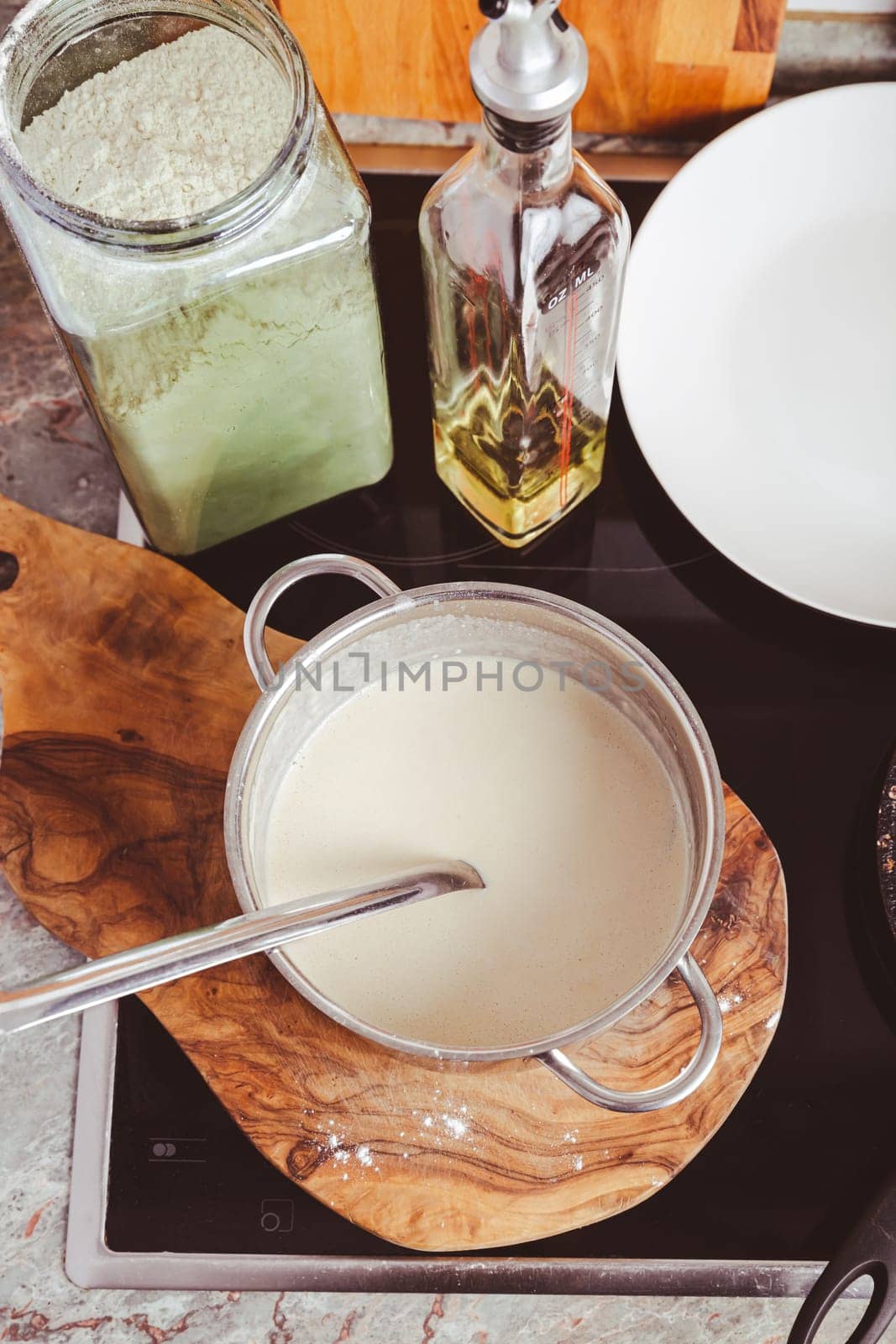 Making thin pancakes on frying pan in kitchen, with cooking dough for crepes and pancakes.