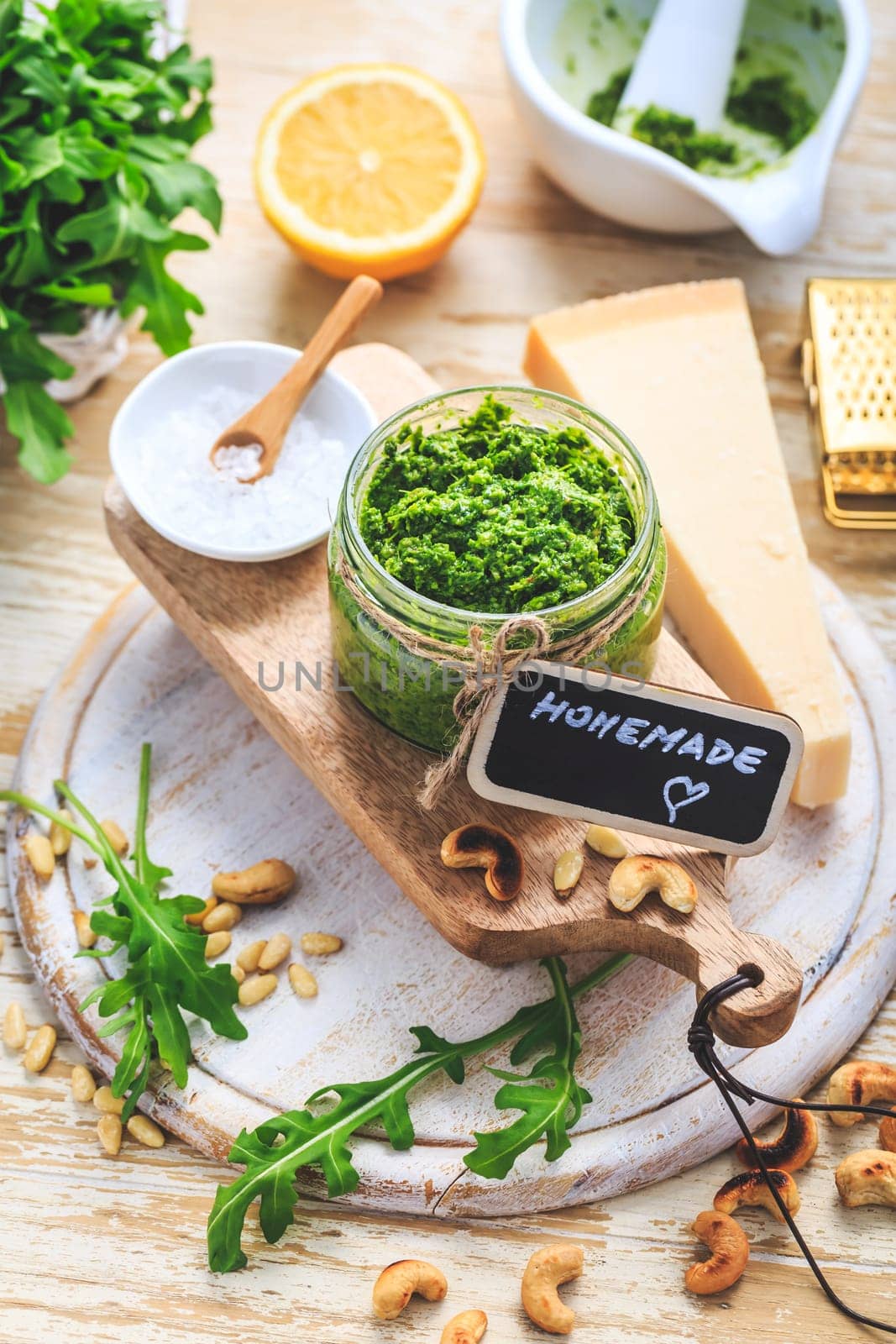 Homemade arugula pesto with ingredients on wooden background