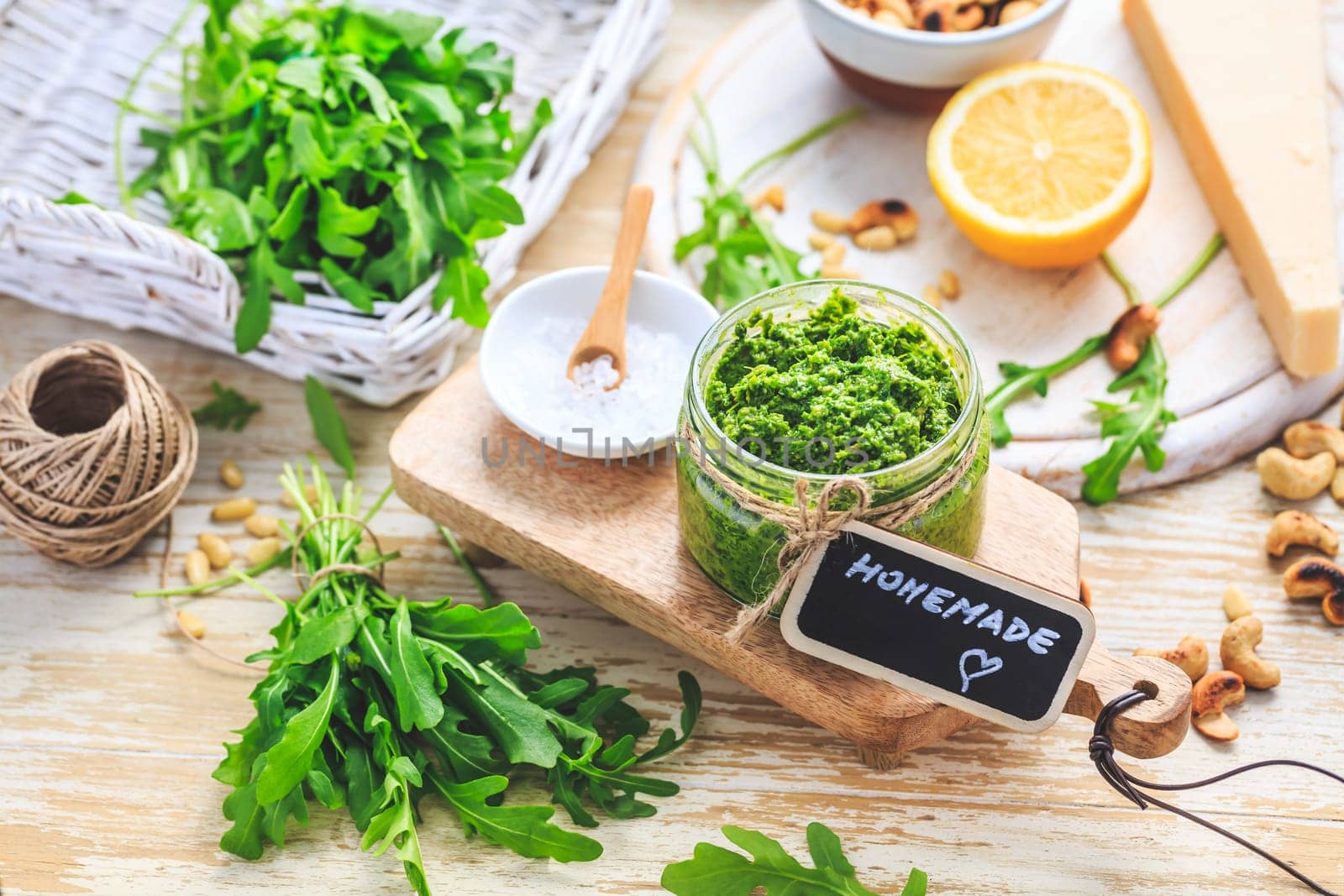 Homemade arugula pesto with ingredients on wooden background