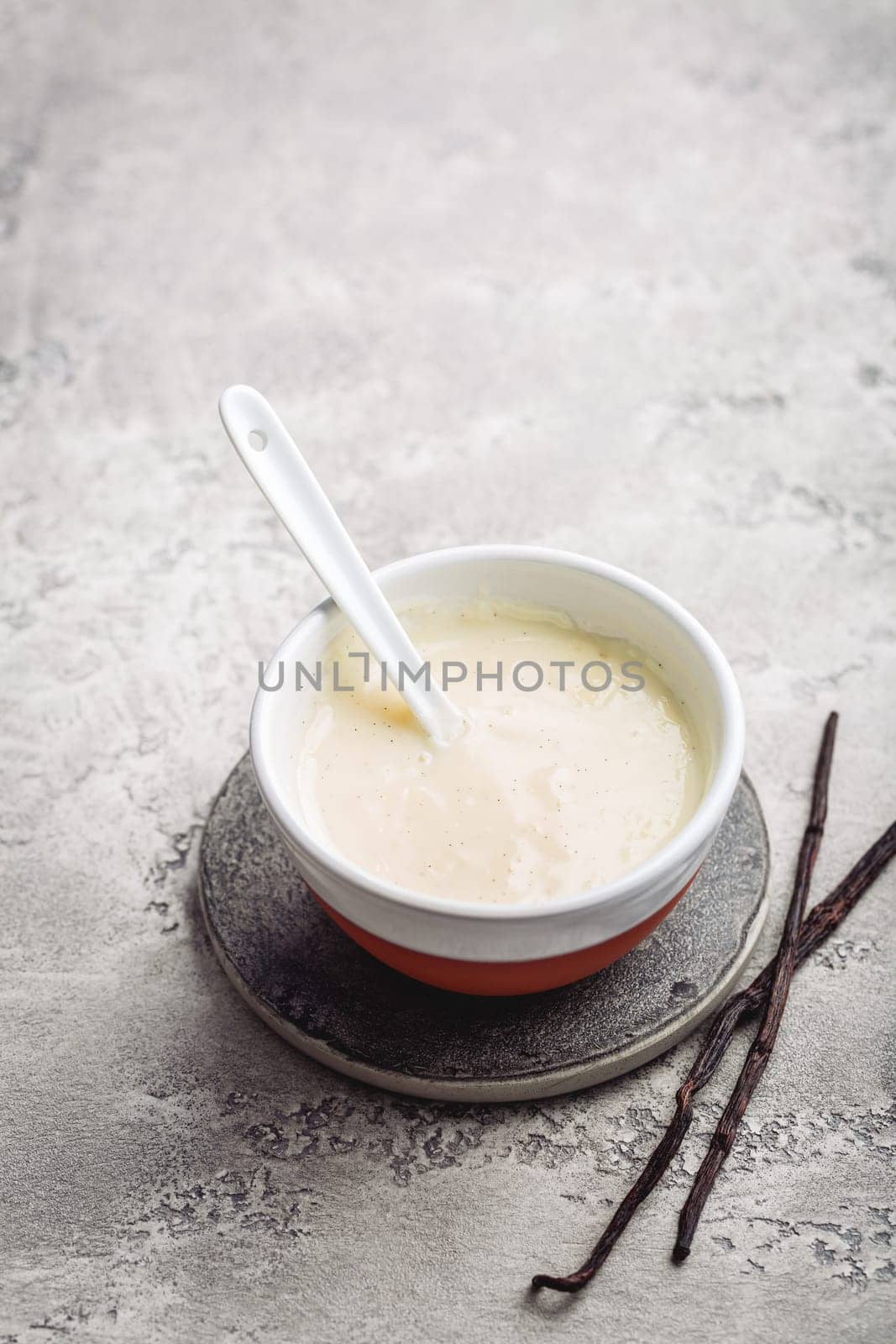 Homemade vanilla sauce in small bowl on grey background