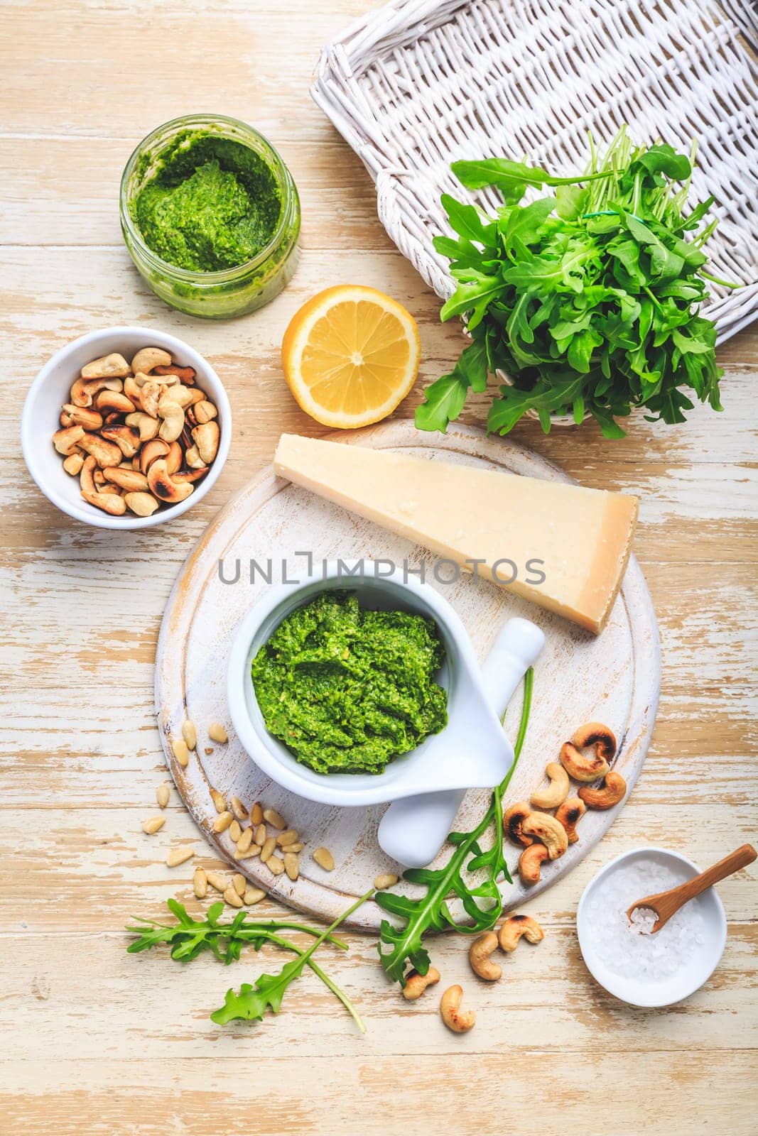 Homemade arugula pesto with ingredients on wooden background