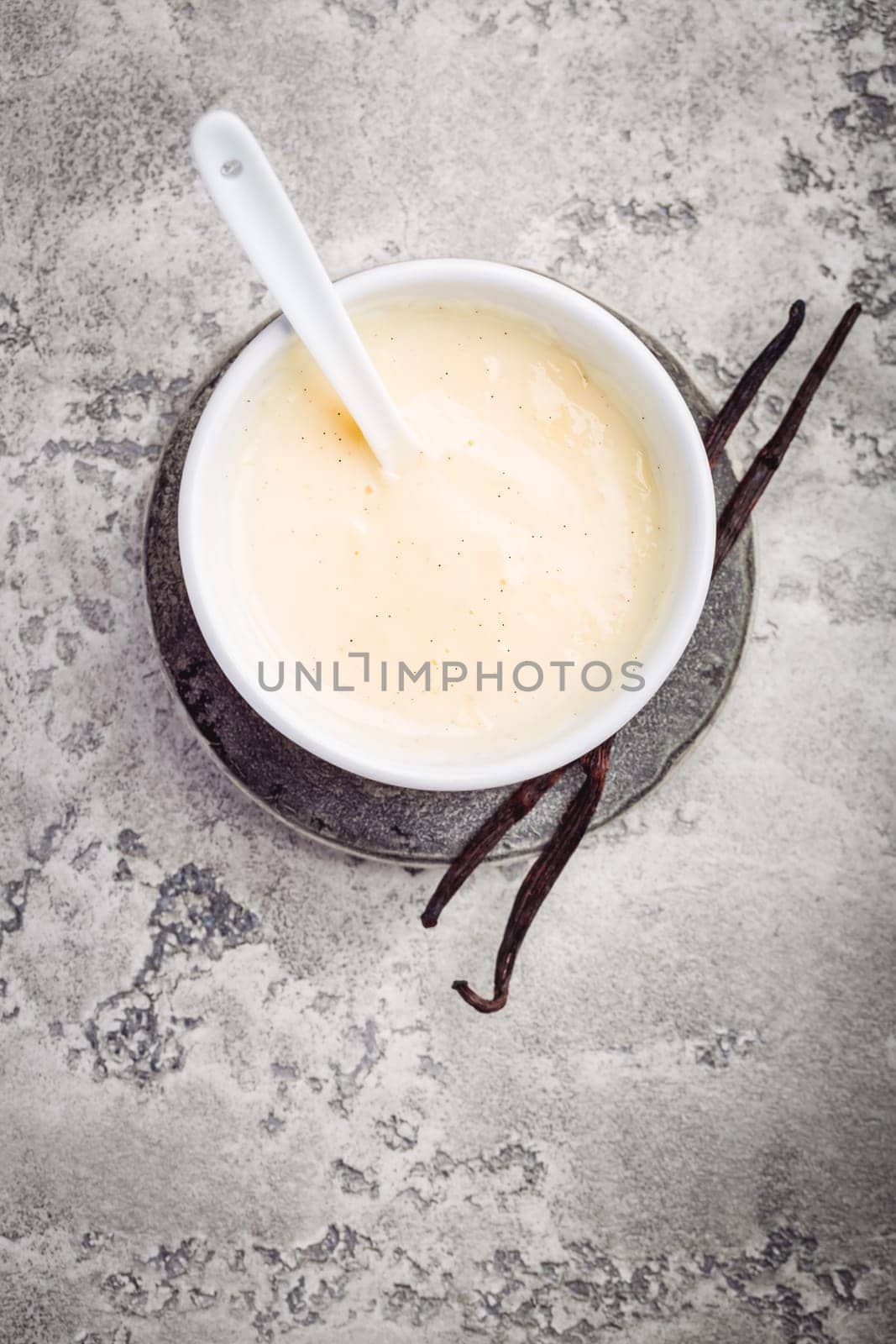 Homemade vanilla sauce in small bowl on grey background