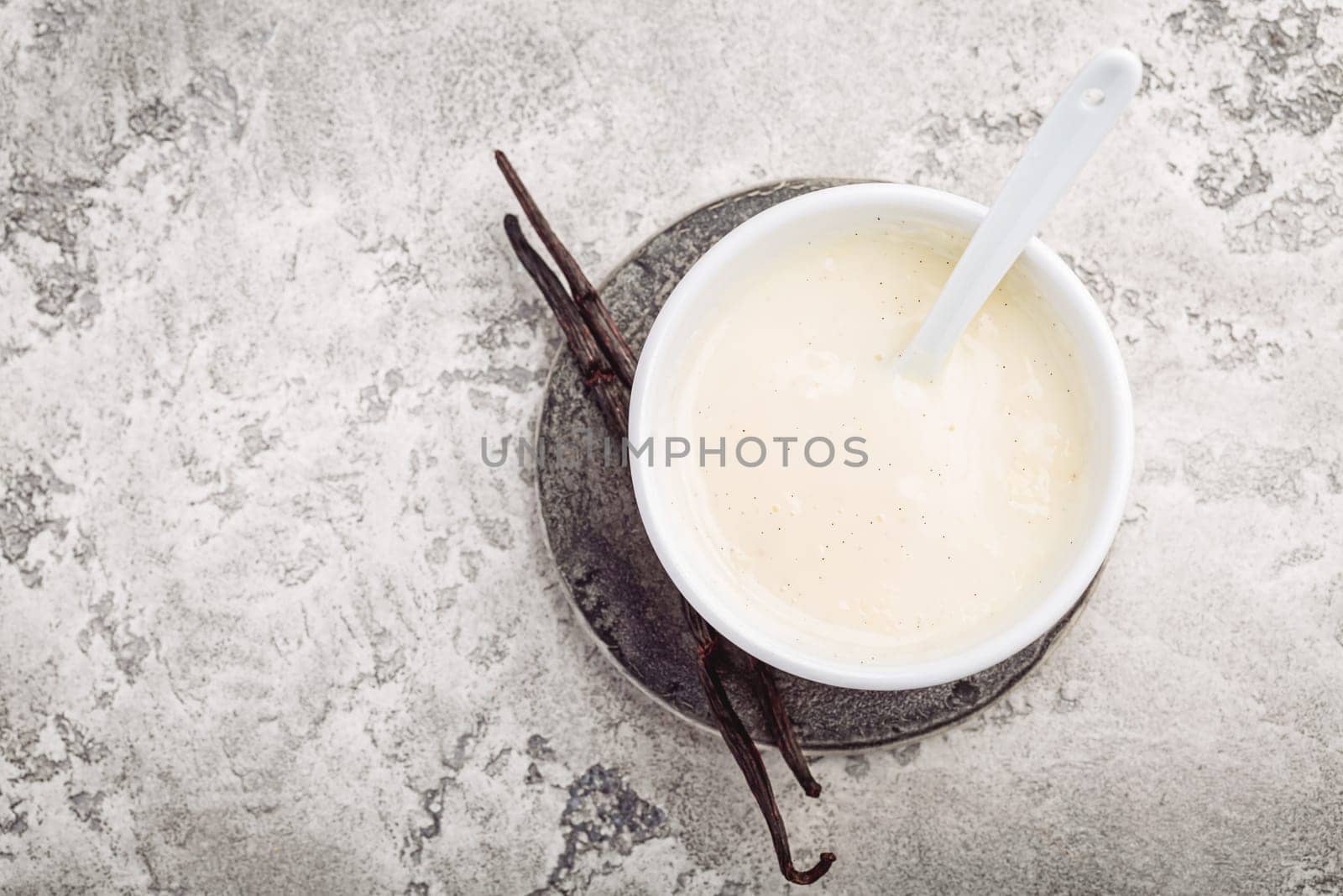 Homemade vanilla sauce in small bowl on grey background