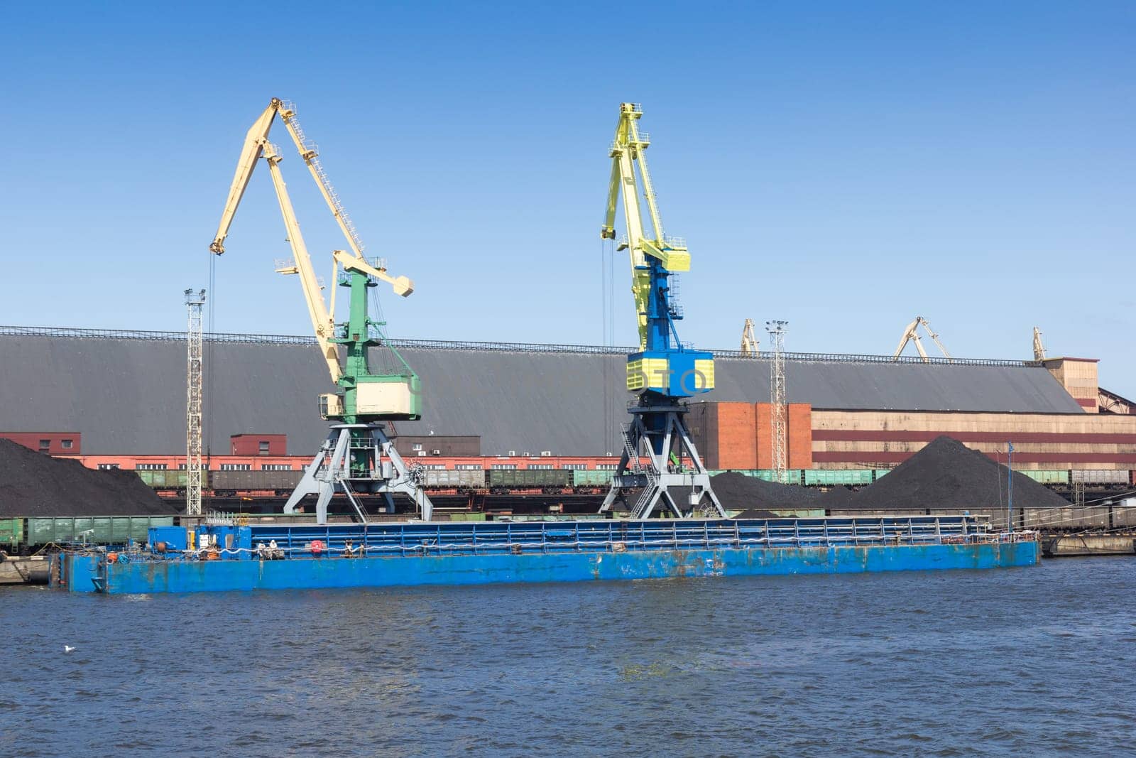 A dry cargo barge is loaded with coal at the port